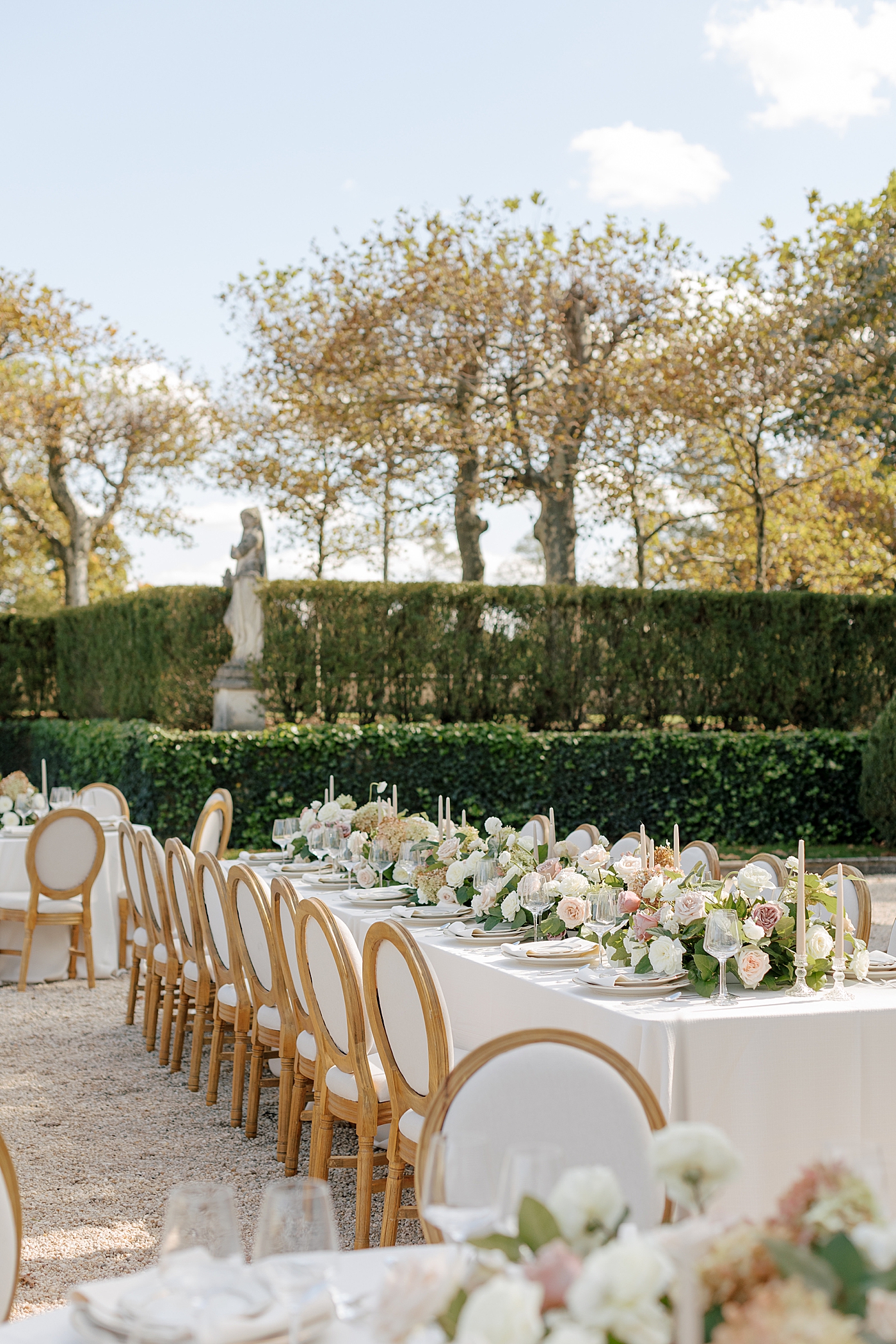 Details of a table setting with white and dusty pink flowers and white table cloths in a European garden during Oheka castle wedding | Image by Hope Helmuth Photography