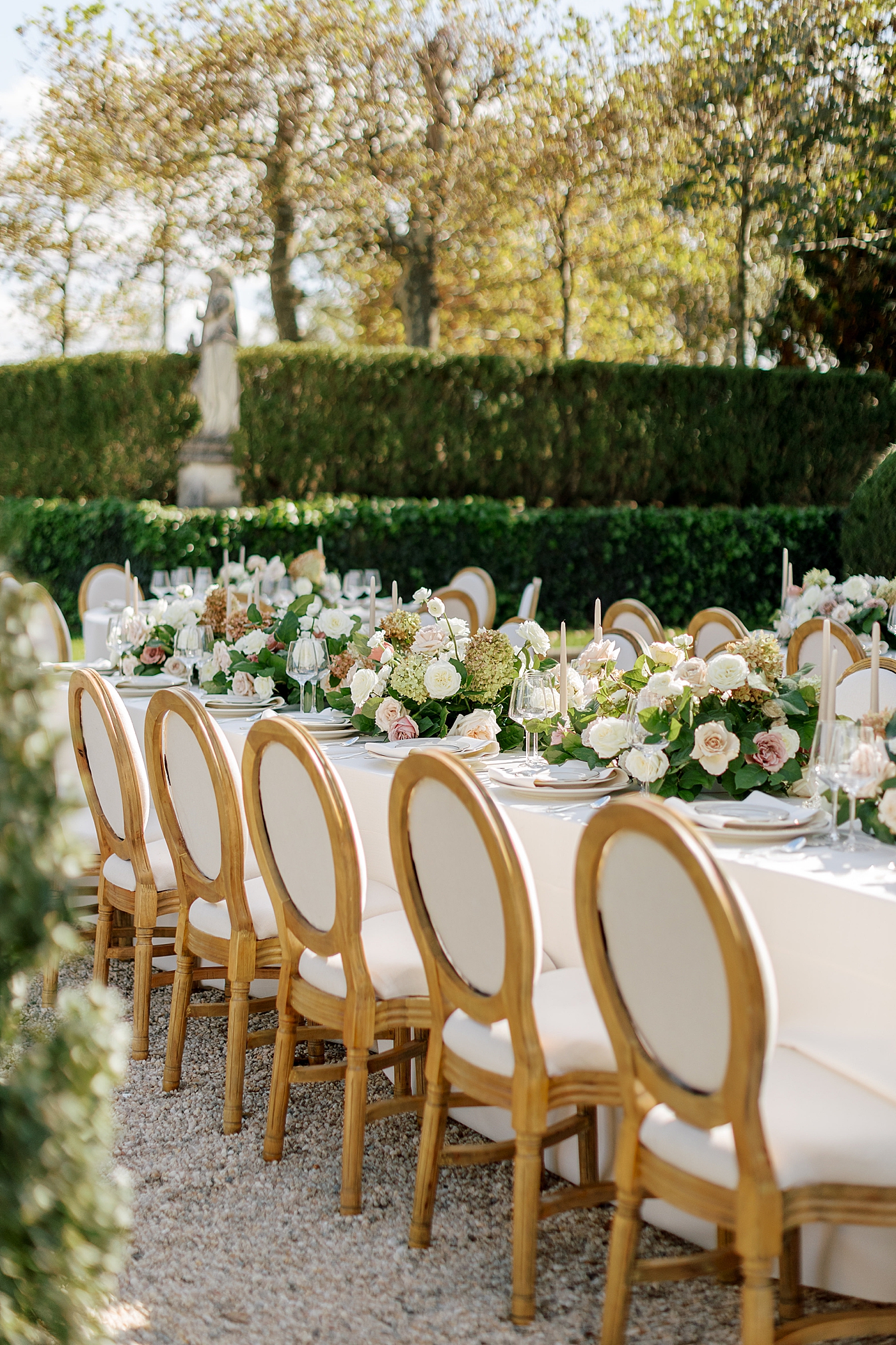 Details of a table setting with white and dusty pink flowers and white table cloths in a European garden during Oheka castle wedding | Image by Hope Helmuth Photography