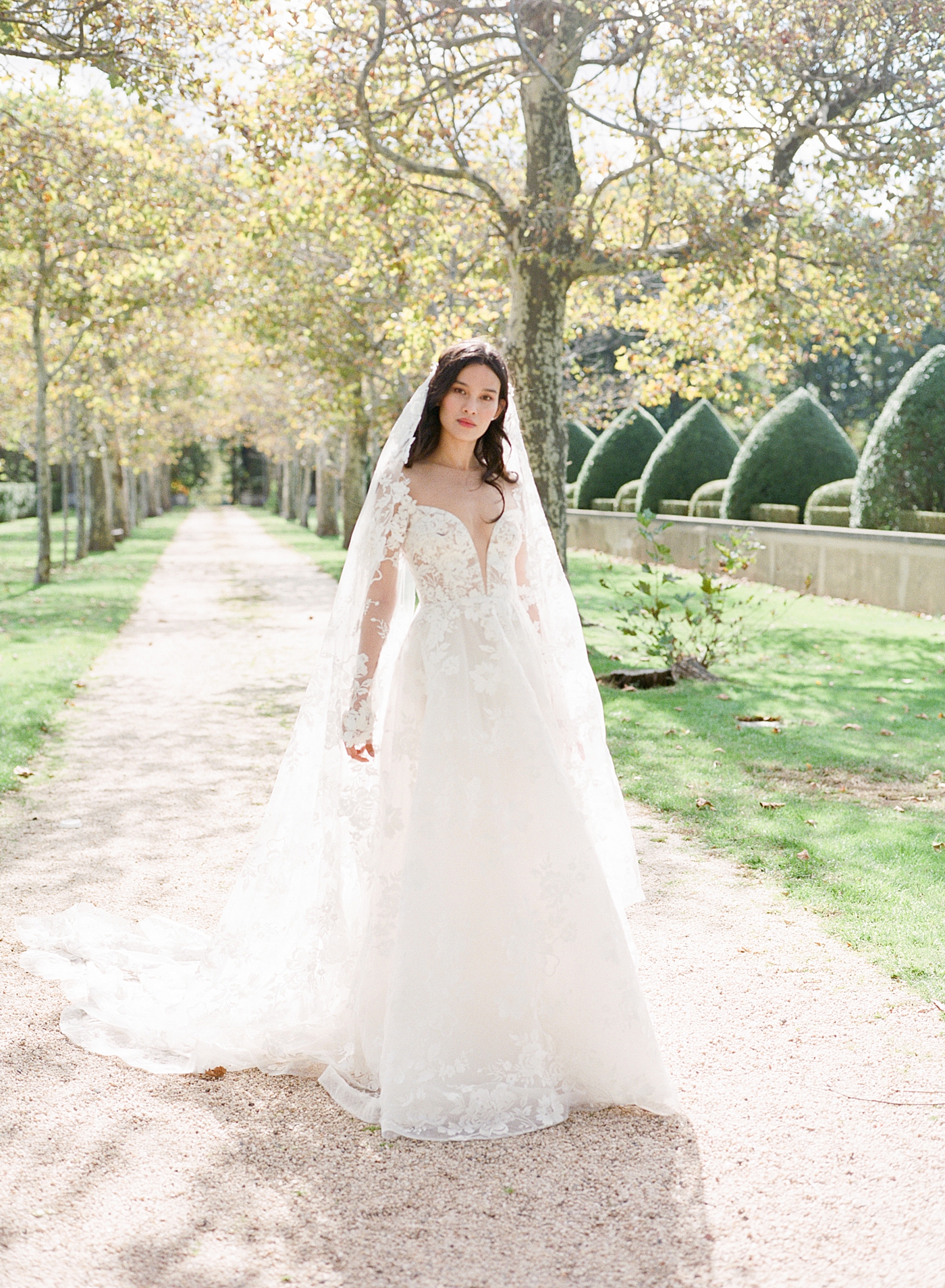 Bridal portrait at the end of a tree-lined driveway during Oheka castle wedding | Image by Hope Helmuth Photography