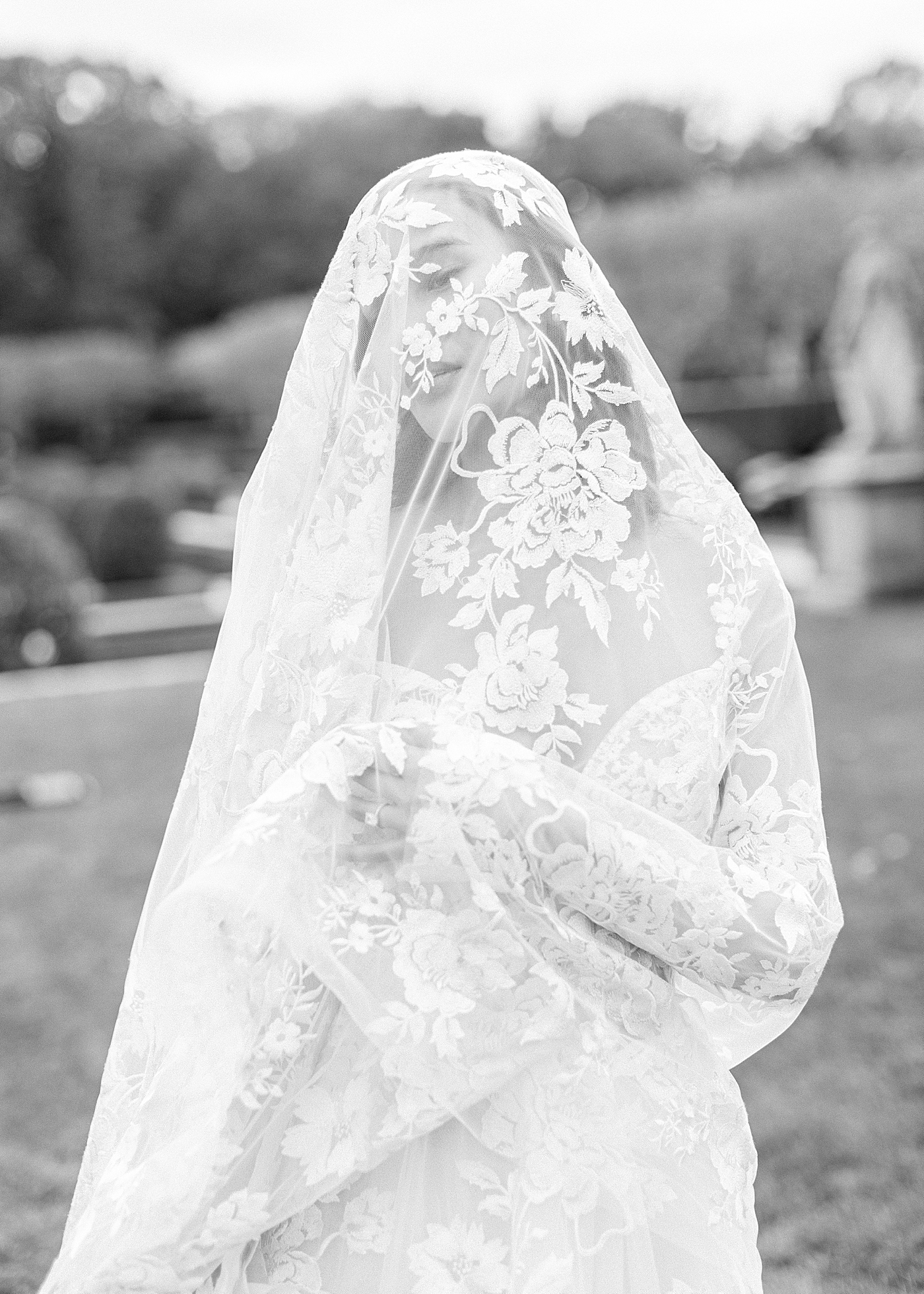 Black and white image of a bride with a veil covering her face | Image by Hope Helmuth Photography