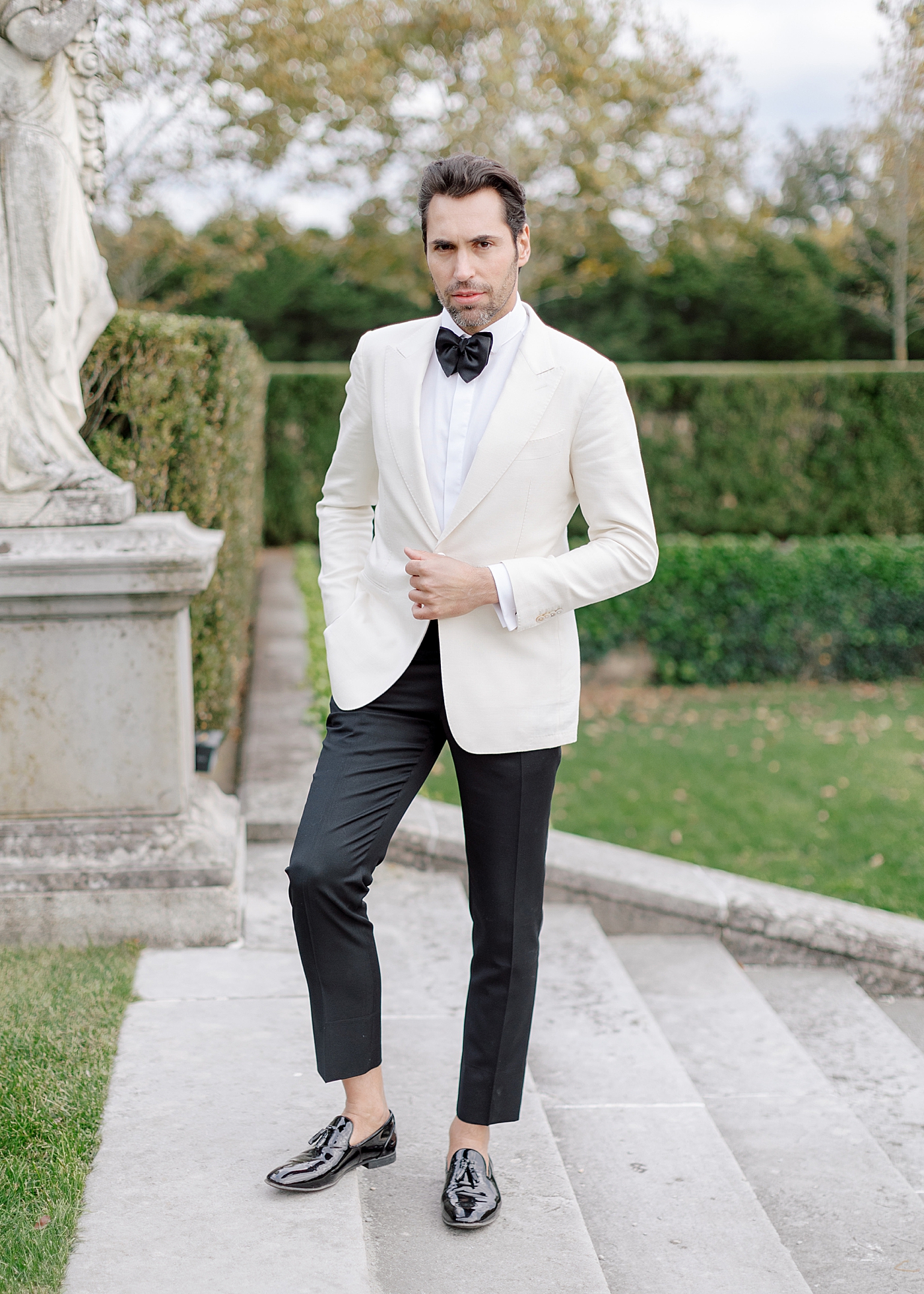 Groom posing on steps during Oheka castle wedding | Image by Hope Helmuth Photography