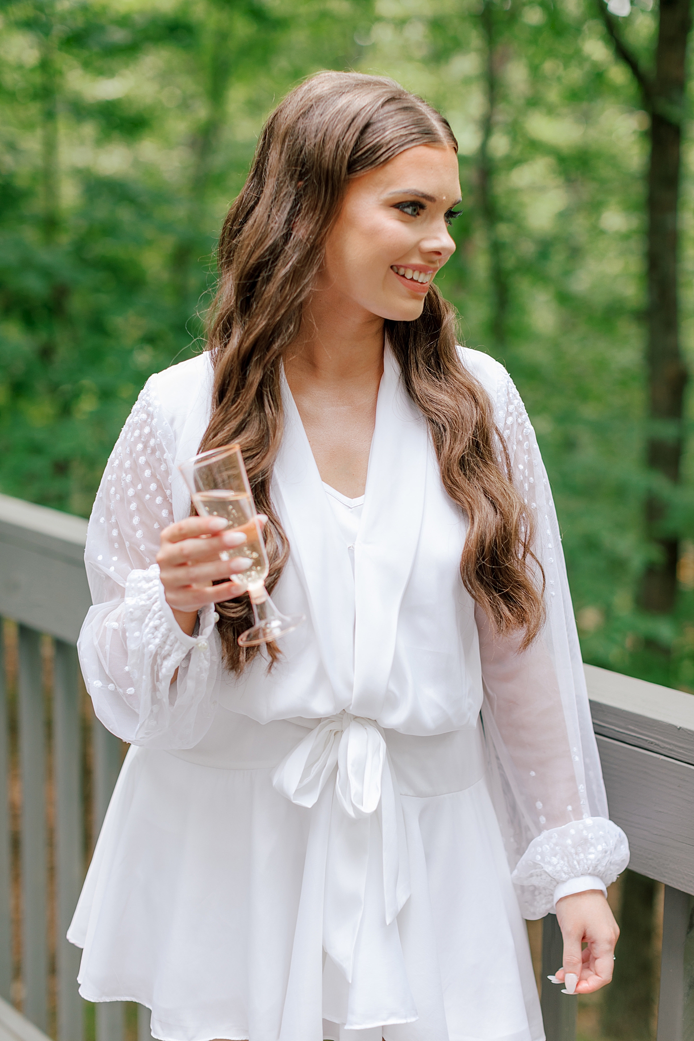 Bride in a lace robe with a champagne flute | Image by Hope Helmuth Photography 