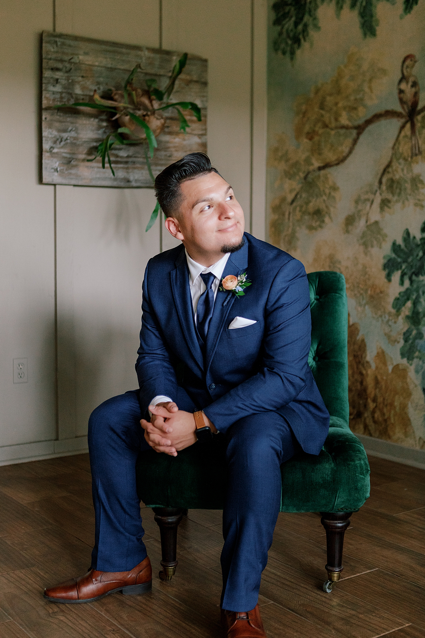 Groom smiling sitting in a green chair | Image by Hope Helmuth Photography 