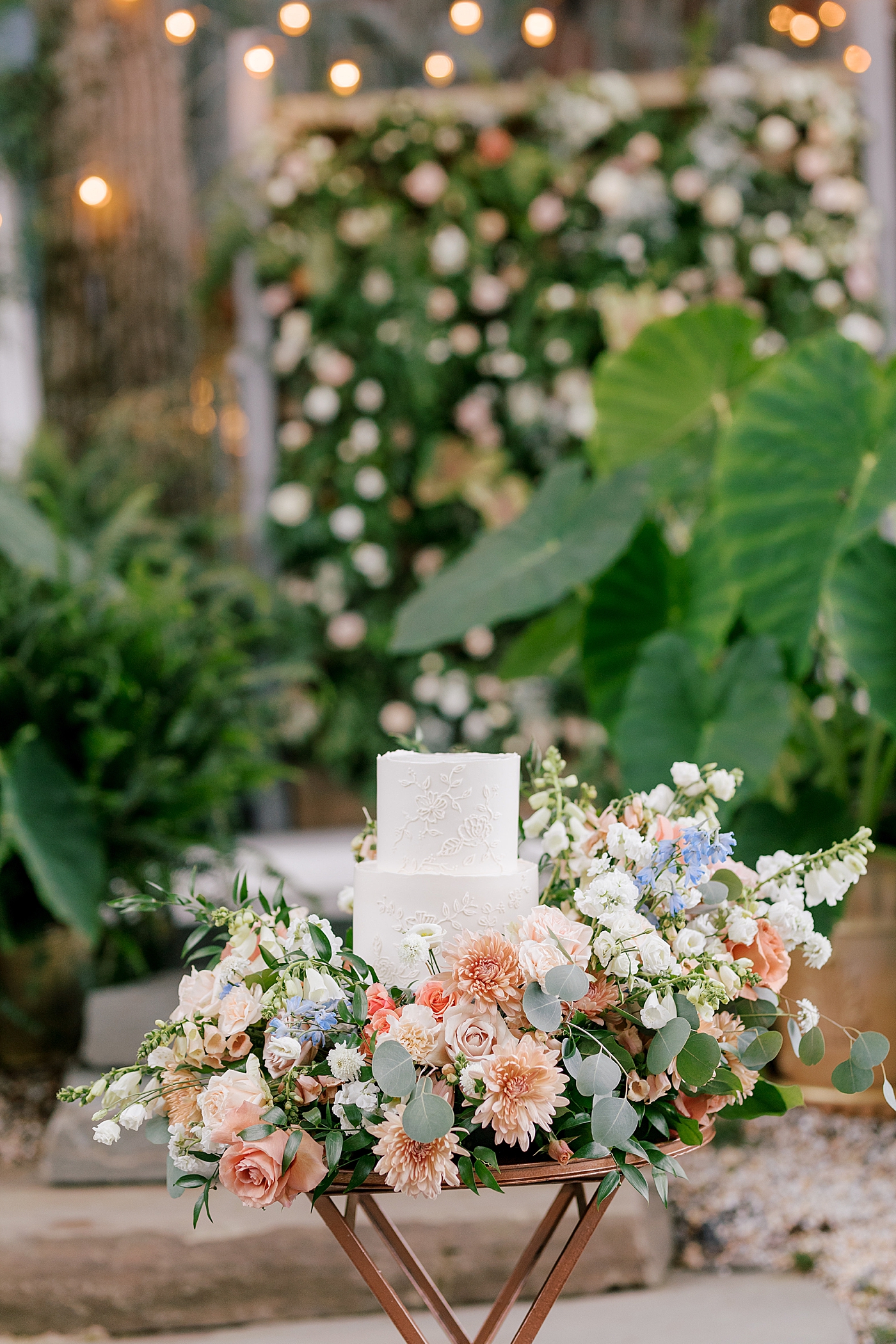 White wedding cake on a table with flowers during Promise Ridge Wedding | Image by Hope Helmuth Photography 
