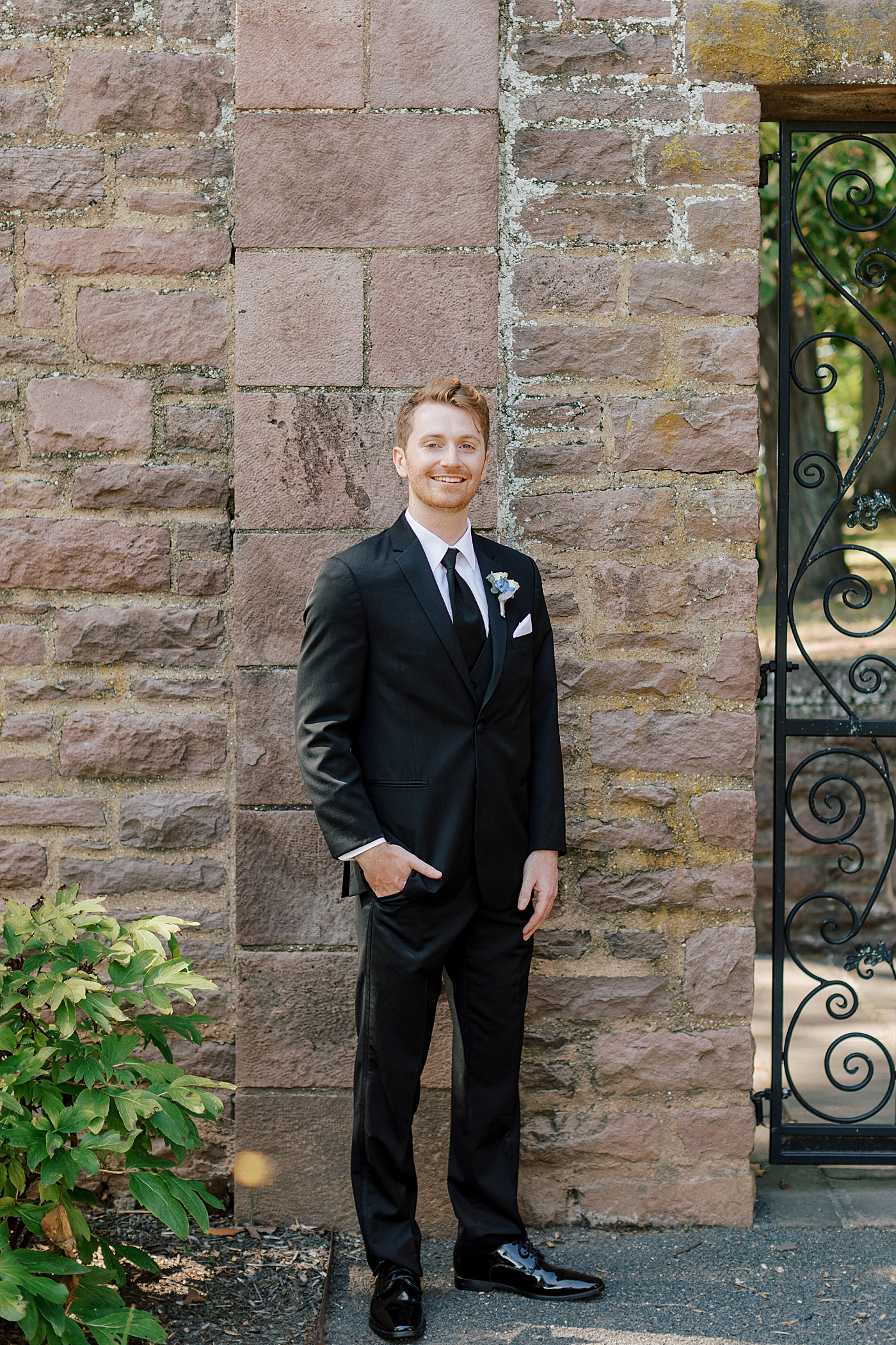 Groom posing in black suit during Tyler Gardens Wedding | Image by Hope Helmuth Photography