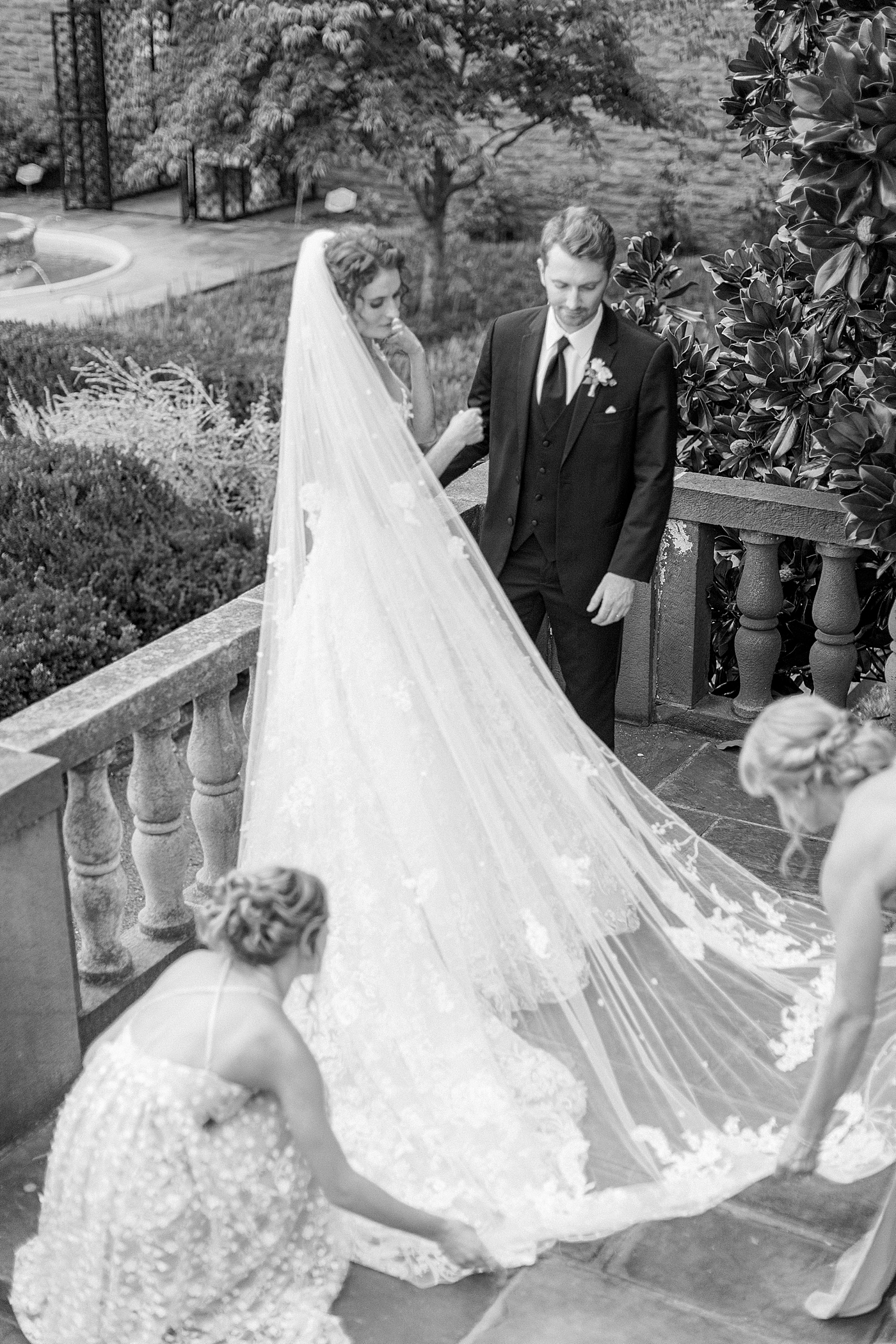 Black and white image of bridesmaids helping bride with her veil during Tyler Gardens Wedding | Image by Hope Helmuth Photography