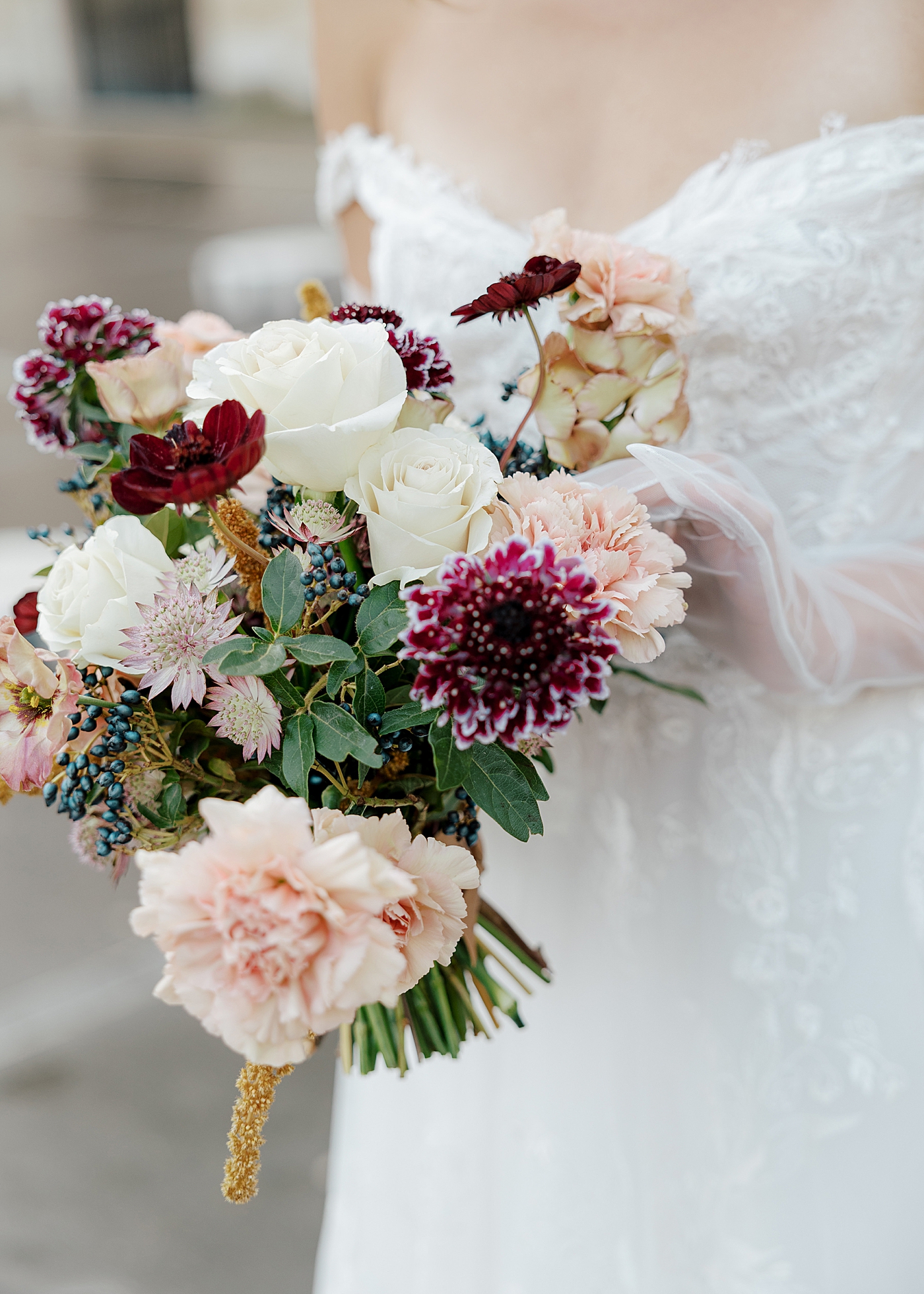 Detail of a bride holding a bridal bouquet with muted burgundy, navy, and cream colors | Image by Hope Helmuth Photography