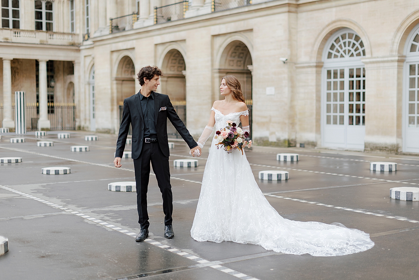Bride and groom starting to walk while looking at each other with a European chateau in the background | Image by Hope Helmuth Photography