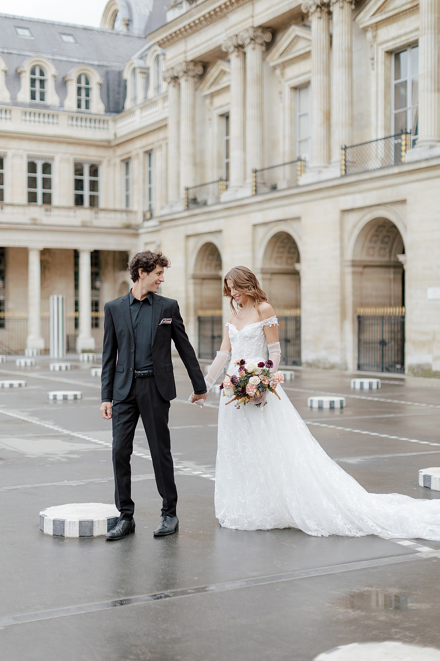 Bride and groom starting to walk while looking in different directions with a European chateau in the background | Image by Hope Helmuth Photography