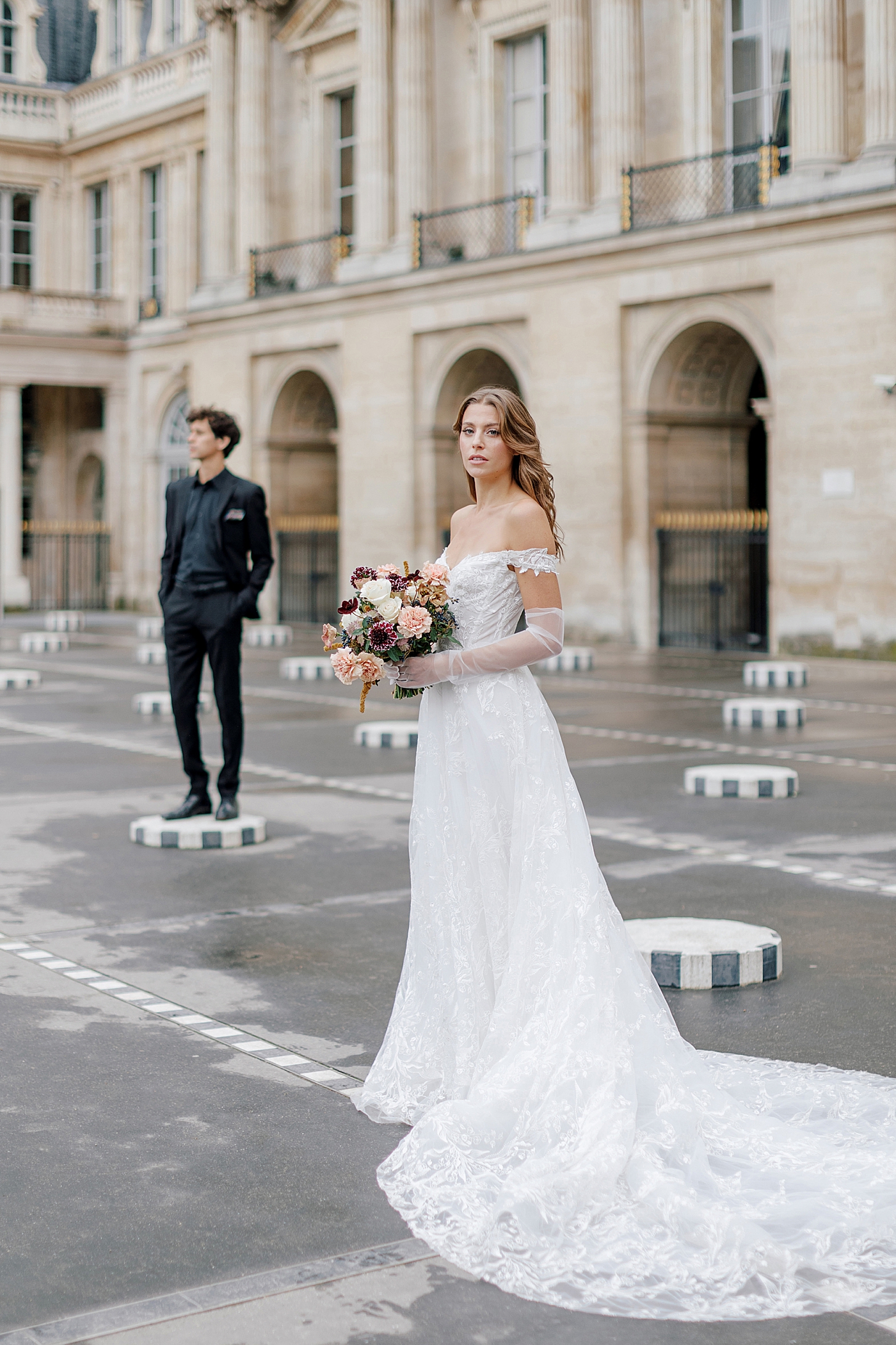 Bride and groom standing separately while looking at the camera with a European chateau in the background | Image by Hope Helmuth Photography