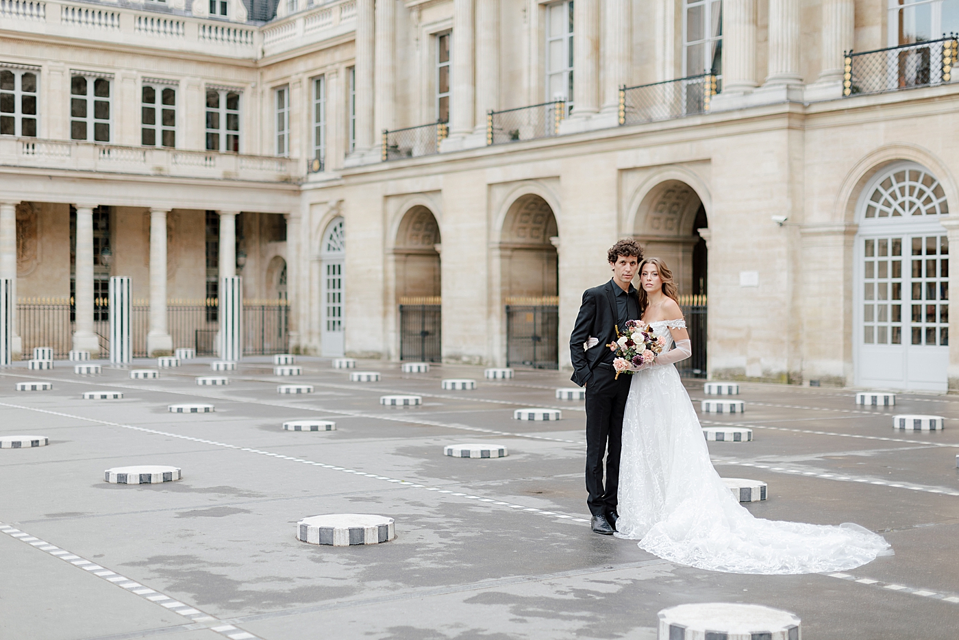 Image of a bride and groom embracing and looking at the camera with a European chateau in the background | Image by Hope Helmuth Photography