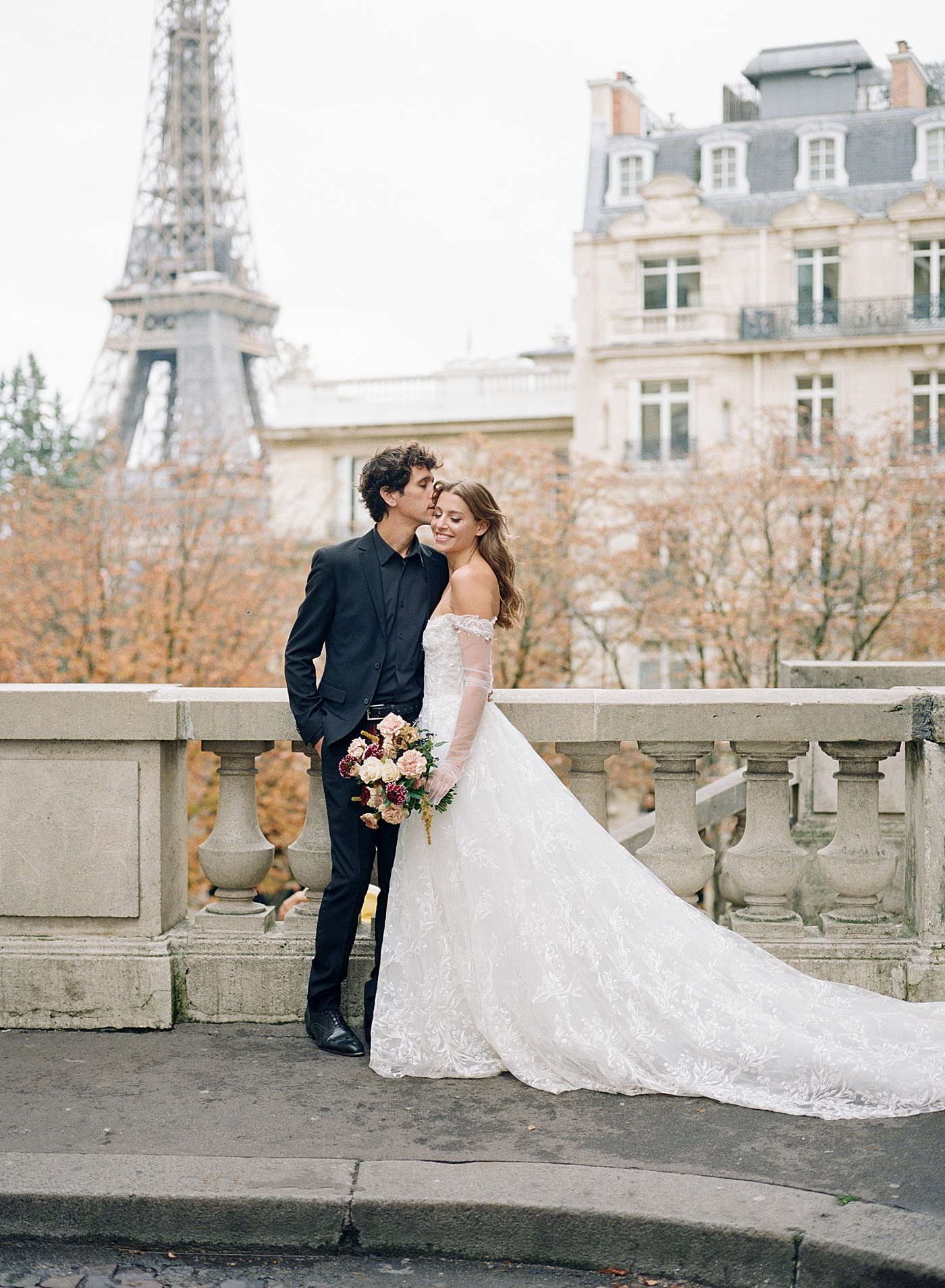 Image of a bride and groom embracing in Paris with the Eiffel tower in the background | Image by Hope Helmuth Photography
