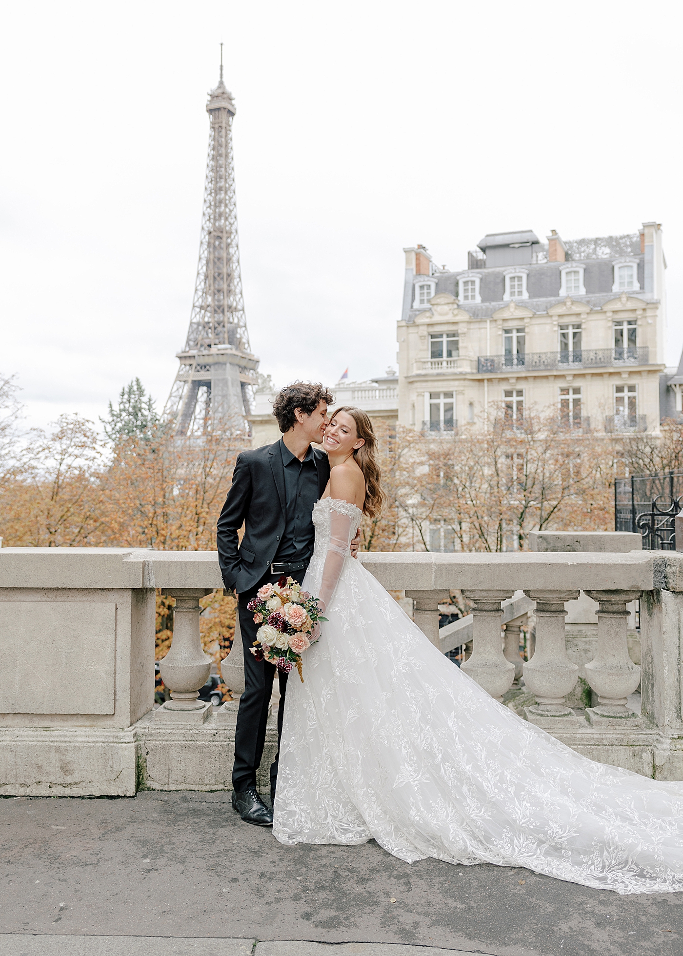 Image of a bride and groom embracing and kissing in Paris with the Eiffel tower in the background | Image by Hope Helmuth Photography