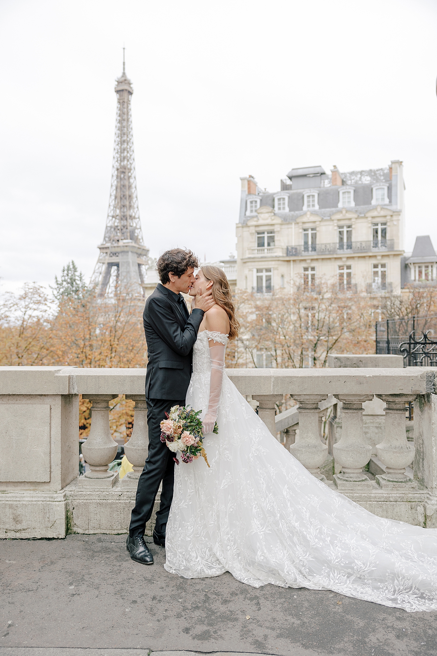 Image of a bride and groom embracing and kissing in Paris with the Eiffel tower in the background | Image by Hope Helmuth Photography