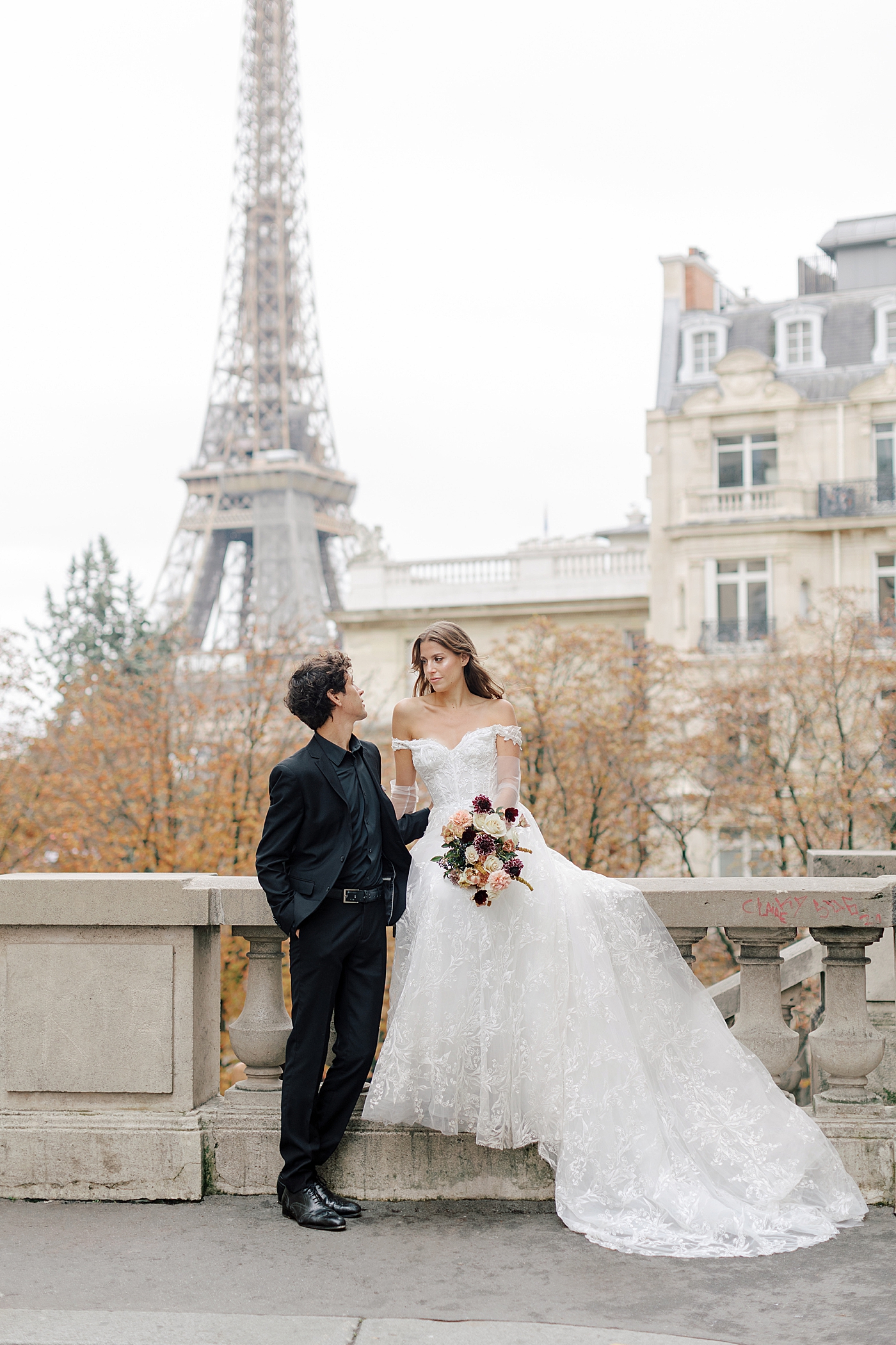Image of a bride and groom standing closely and looking at each other in Paris with the Eiffel tower in the background | Image by Hope Helmuth Photography
