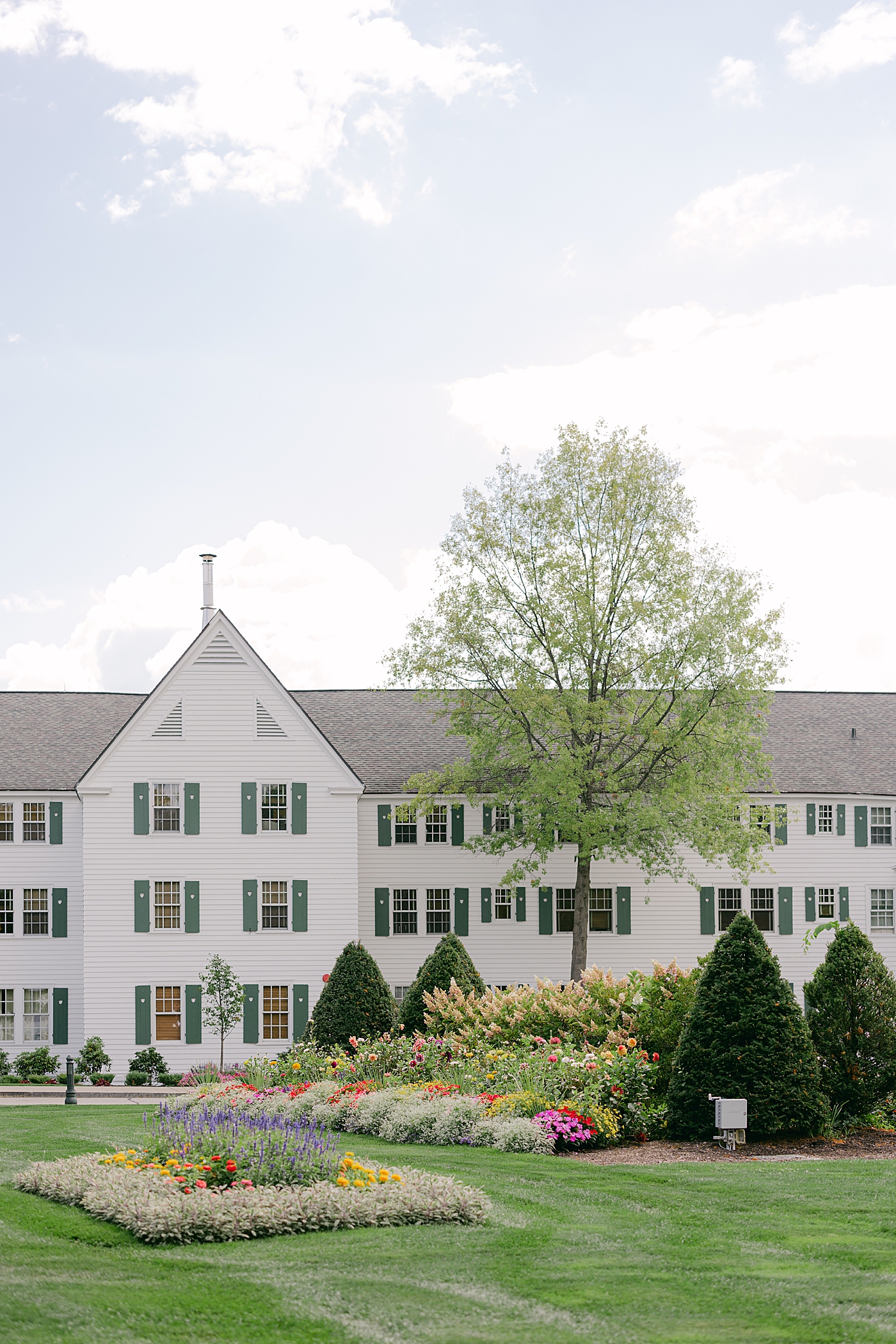 Location image of the front of Sagamore country club with floral landscaping during their Sagamore Wedding | Image by Hope Helmuth Photography