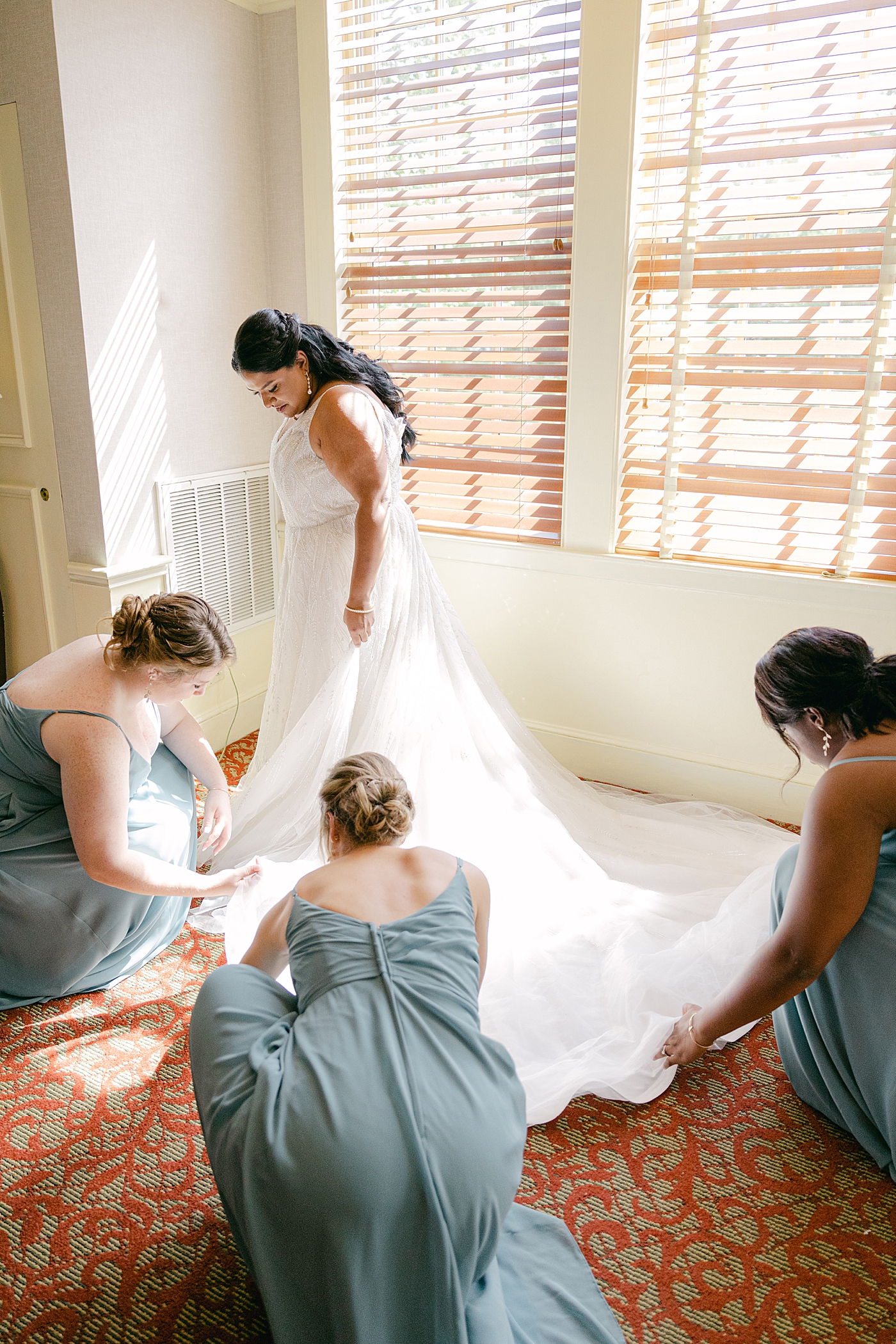 Bridesmaids helping a bride into her wedding dress during their Sagamore Wedding | Image by Hope Helmuth Photography