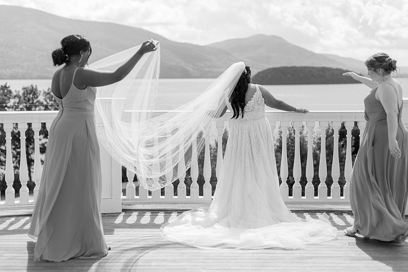 Black and white image of a bridesmaids helping a bride get her vail ready for wedding portraits | Image by Hope Helmuth Photography