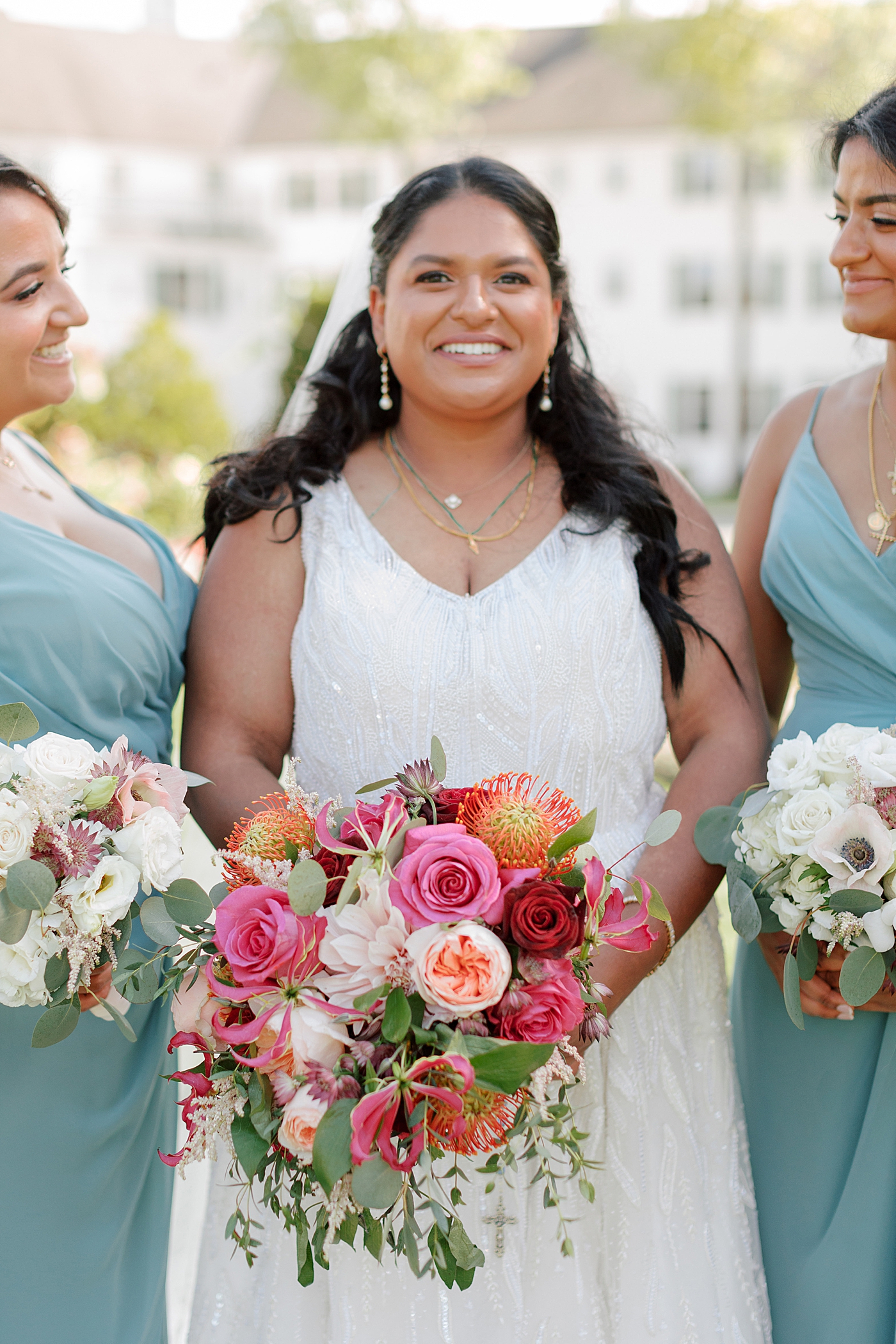 Close up of bride with colorful bouquet with her bridesmaids | Image by Hope Helmuth Photography