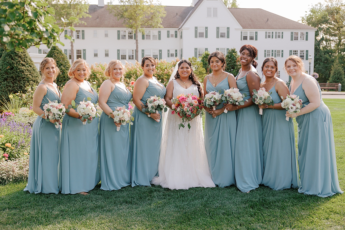 Formal portrait of a bride and her bridesmaids in blue with colorful bouquets | Image by Hope Helmuth Photography