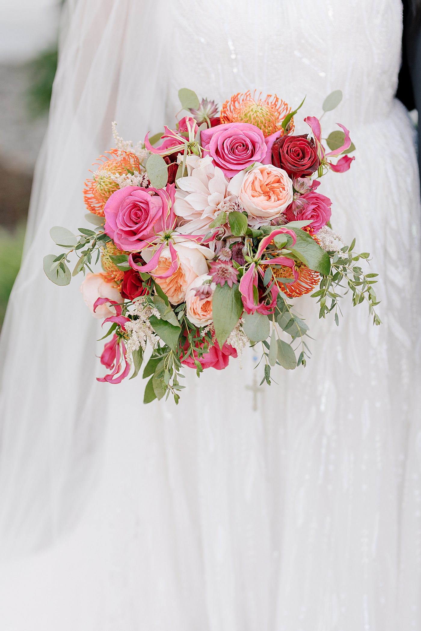 Close up of a colorful pink, orange, and red bridal bouquet | Image by Hope Helmuth Photography