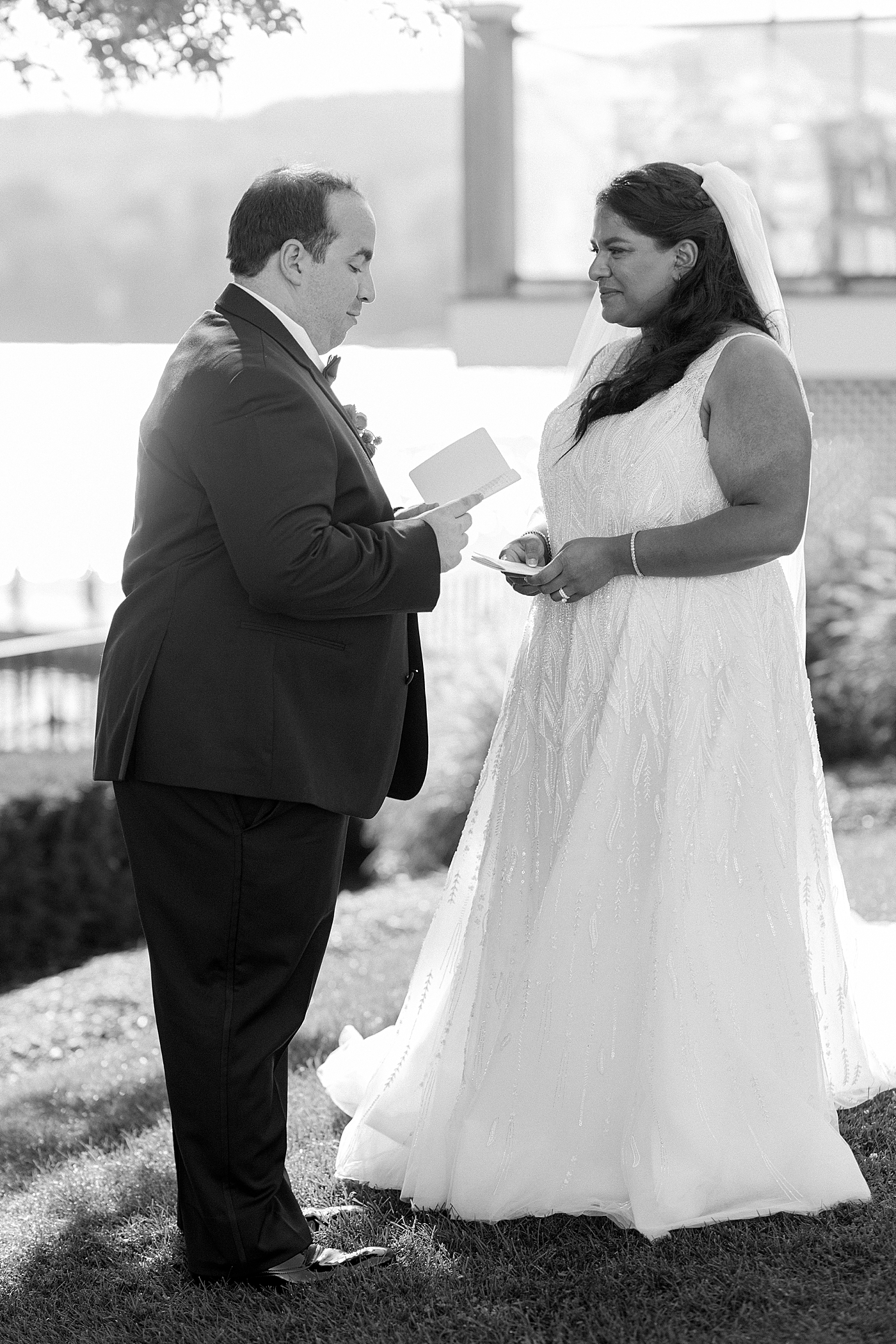 Black and white image of bride and groom reading vows to each other | Image by Hope Helmuth Photography