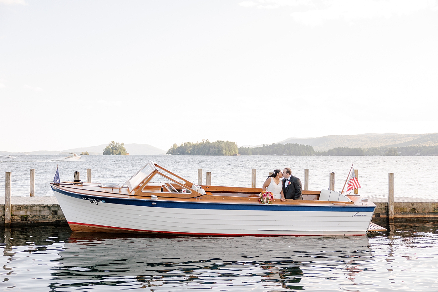 Bride and groom kissing on the back of a wooden boat | Image by Hope Helmuth Photography