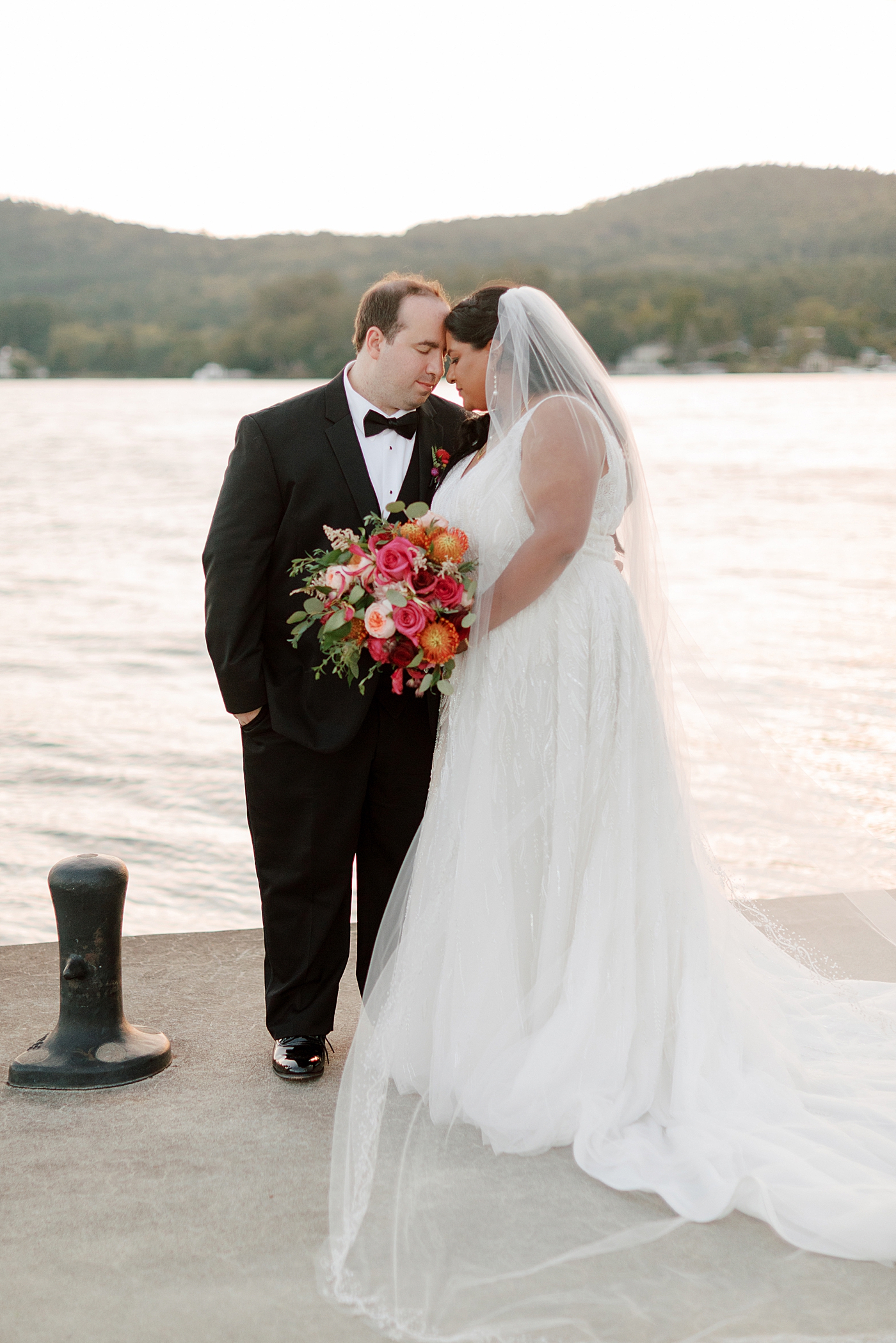 Bride and groom posing, heads together on a dock at sunset during their Sagamore Wedding | Image by Hope Helmuth Photography