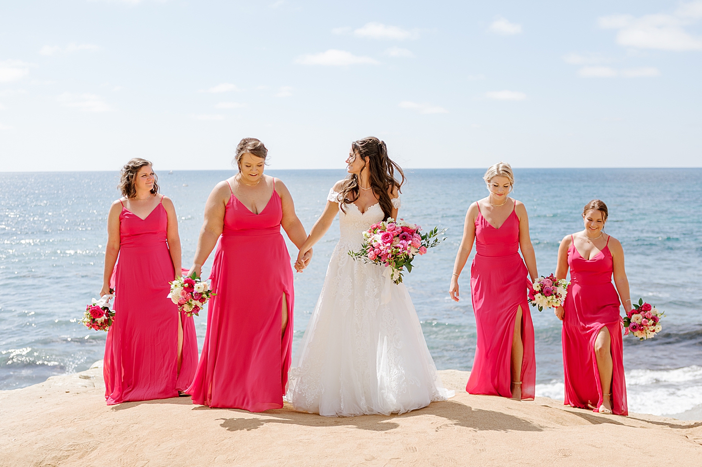 Bride and bridesmaids in hot pink looking at each other and walking towards the camera | Image by Hope Helmuth Photography