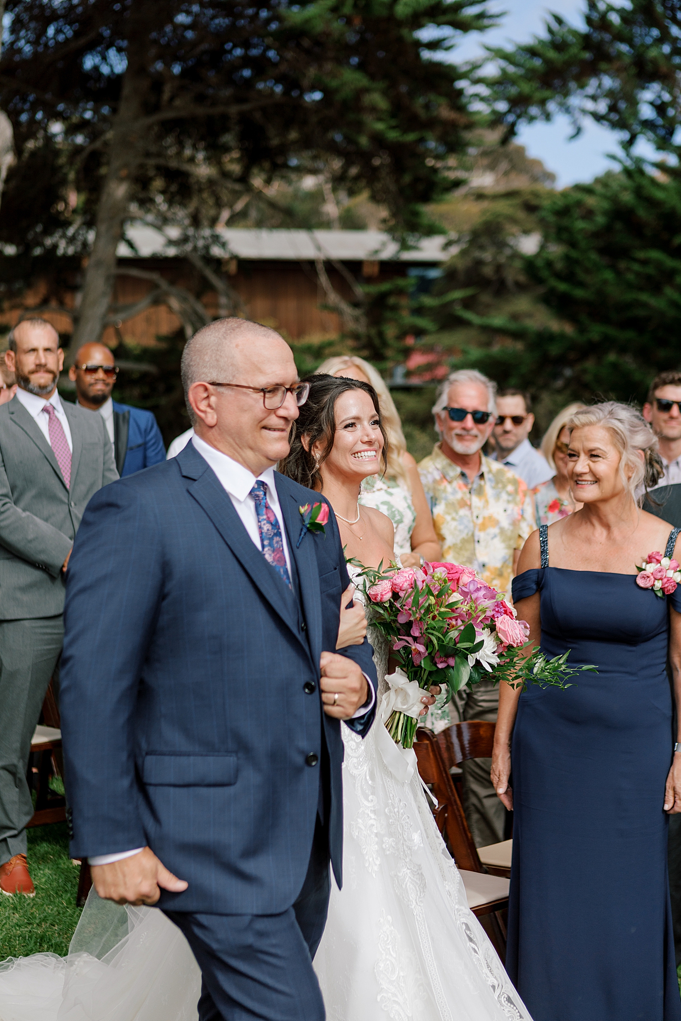 Image of father in navy suit walking the bride down the isle with a bright pink bouquet | Image by San Diego Wedding Photographer Hope Helmuth
