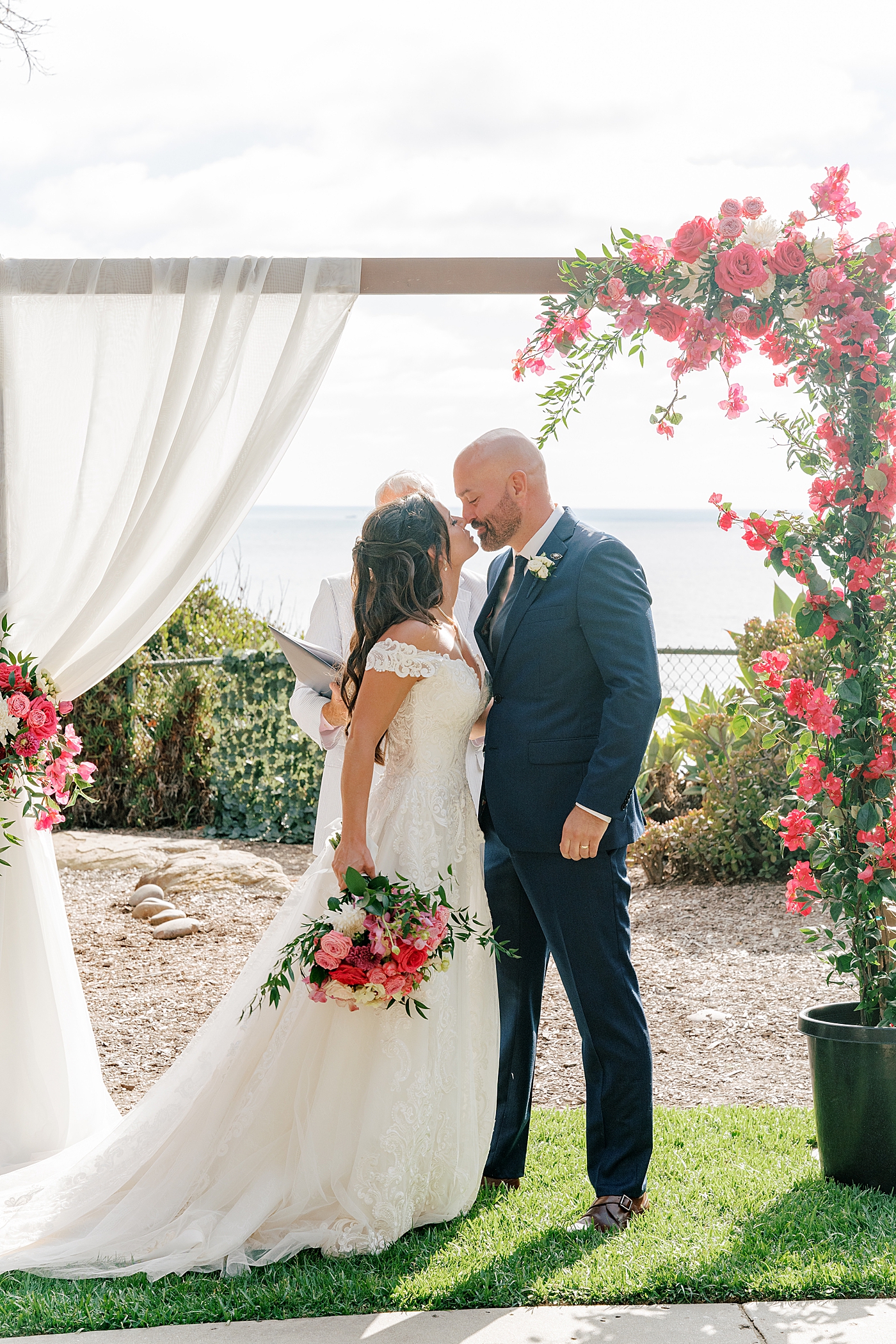 Backlit image of the bride and groom about to kiss at the wedding arch | Image by San Diego Wedding Photographer Hope Helmuth
