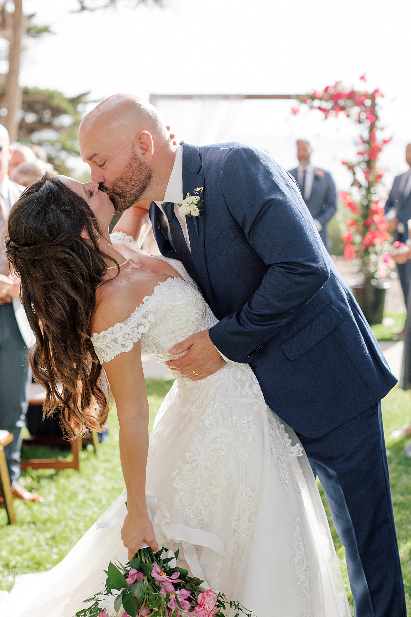 Backlit image of the groom dipping and kissing his bride halfway down the isle | Image by San Diego Wedding Photographer Hope Helmuth