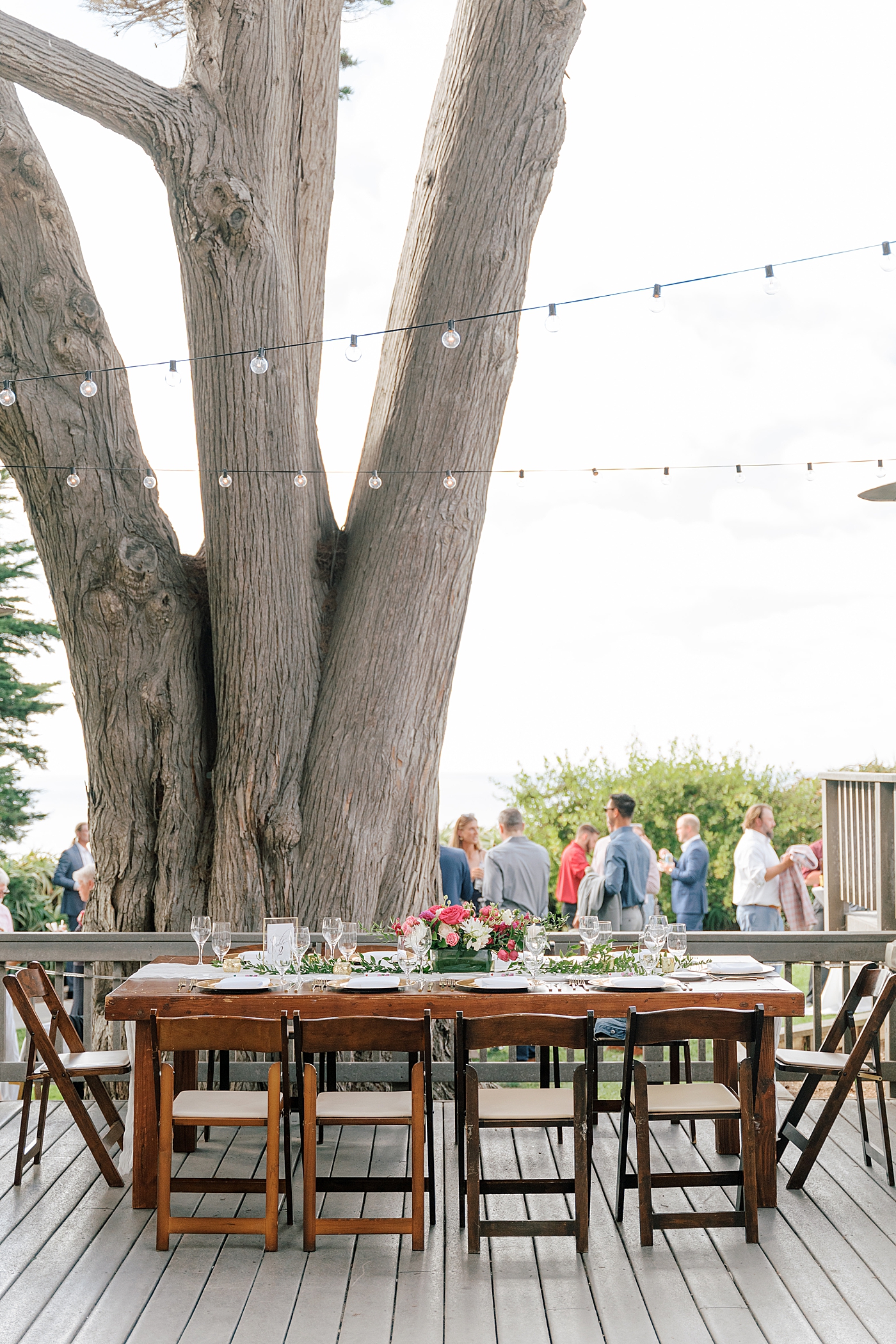 Image of an empty, but set wooden wedding table with folding chairs and string lights | Image by San Diego Wedding Photographer Hope Helmuth