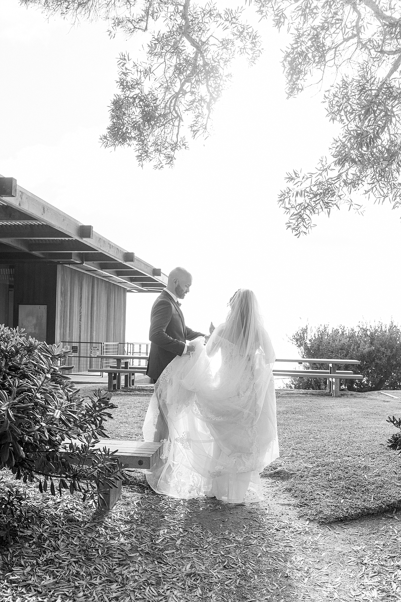 Black and white backlit image of bride and groom walking away from the camera | Image by San Diego Wedding Photographer Hope Helmuth