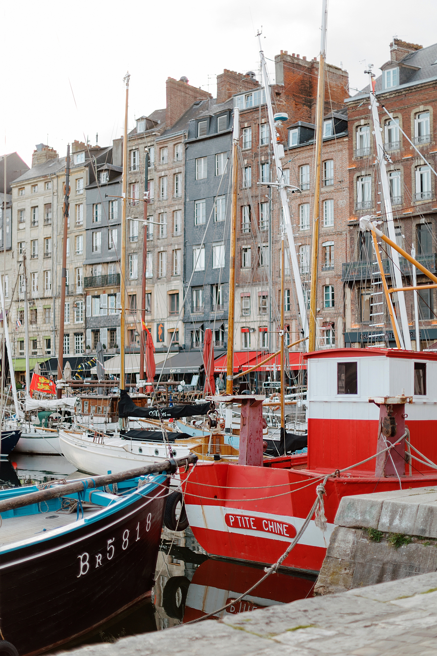 Tall, multistory homes and docked sailboats on the opposite side of a French canal during a trip with France Wedding Photographer Hope Helmuth Photography