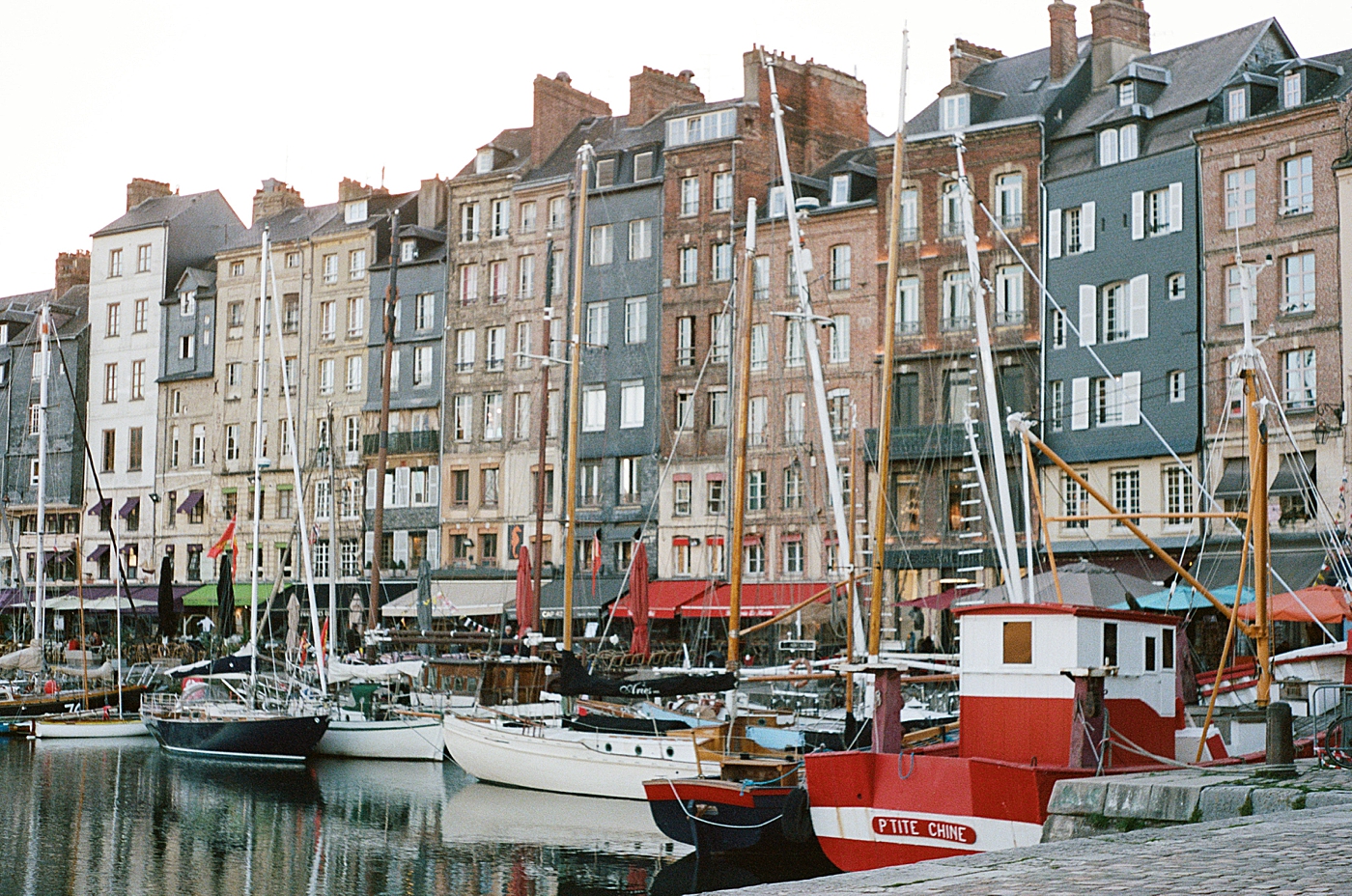 Landscape image of tall, multistory homes and docked boats in a French canal | Image by Hope Helmuth Photography