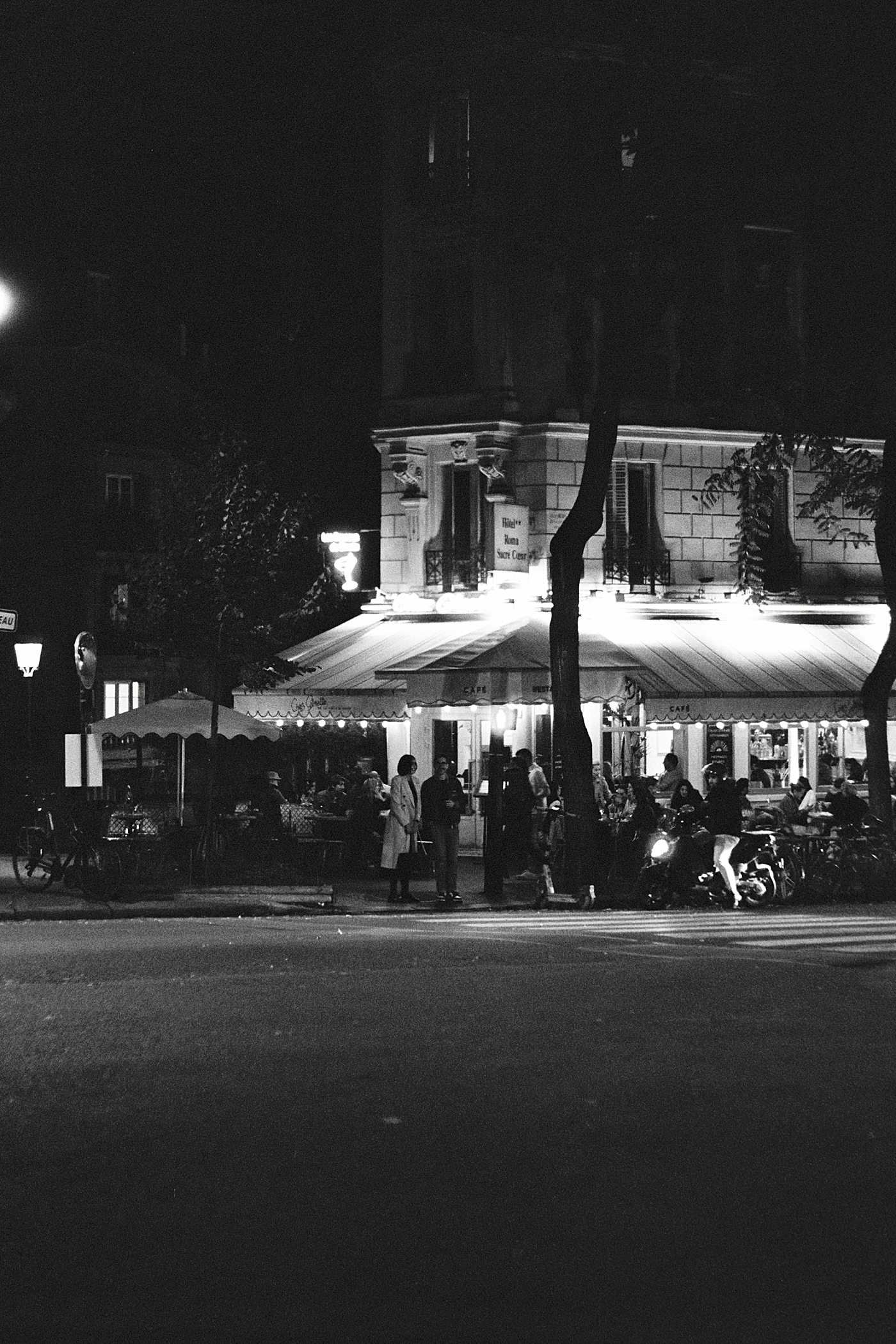Black and white photo of a crowded restaurant at night during a trip with France Wedding Photographer Hope Helmuth Photography