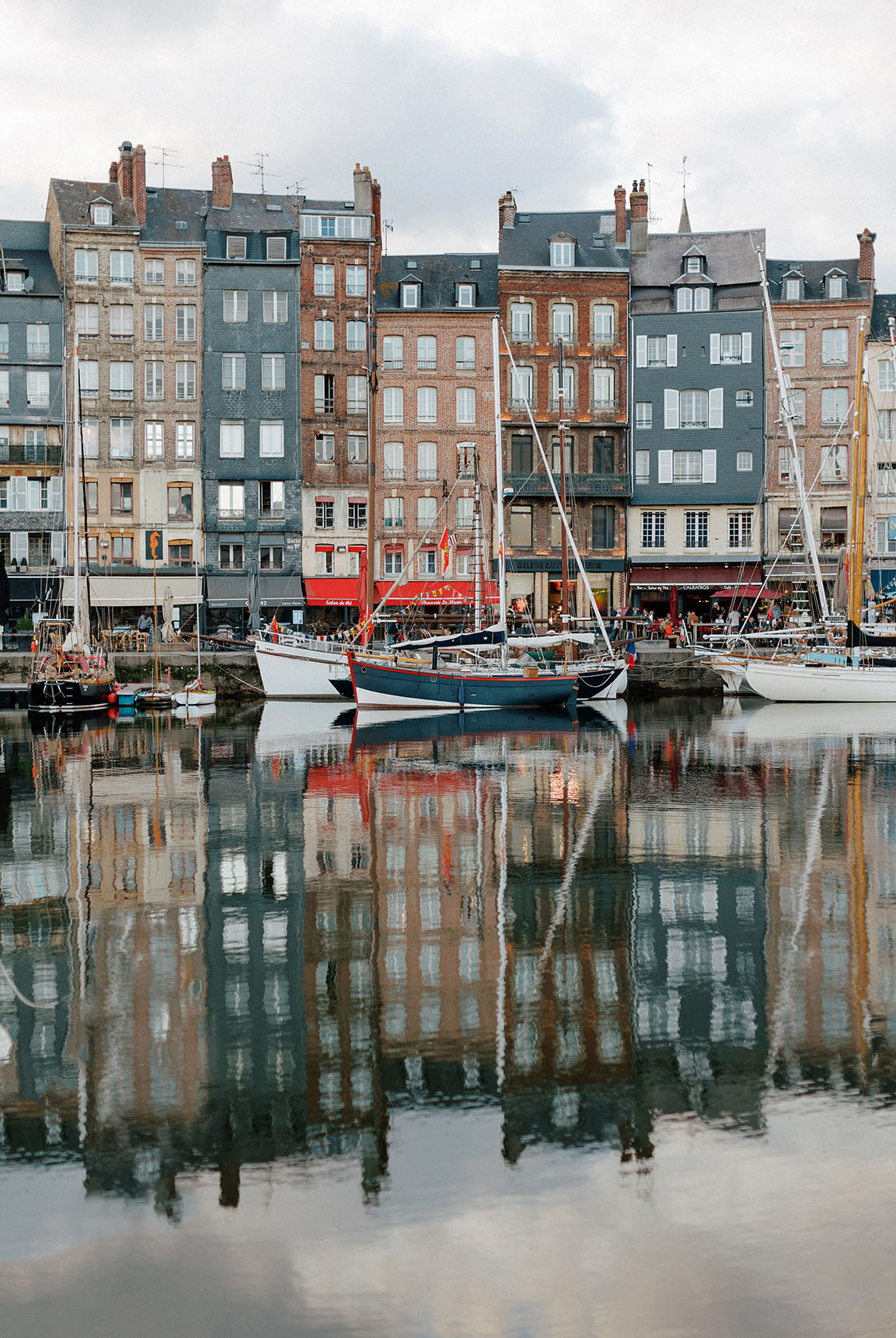 Landscape image of tall, multistory homes and docked boats in a French canal