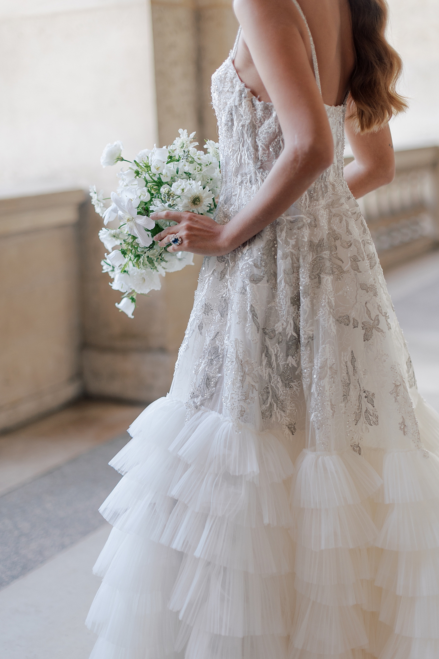 Detail of a bride standing in the outside hallway of the Louvre with a bouquet | Image by Hope Helmuth Photography