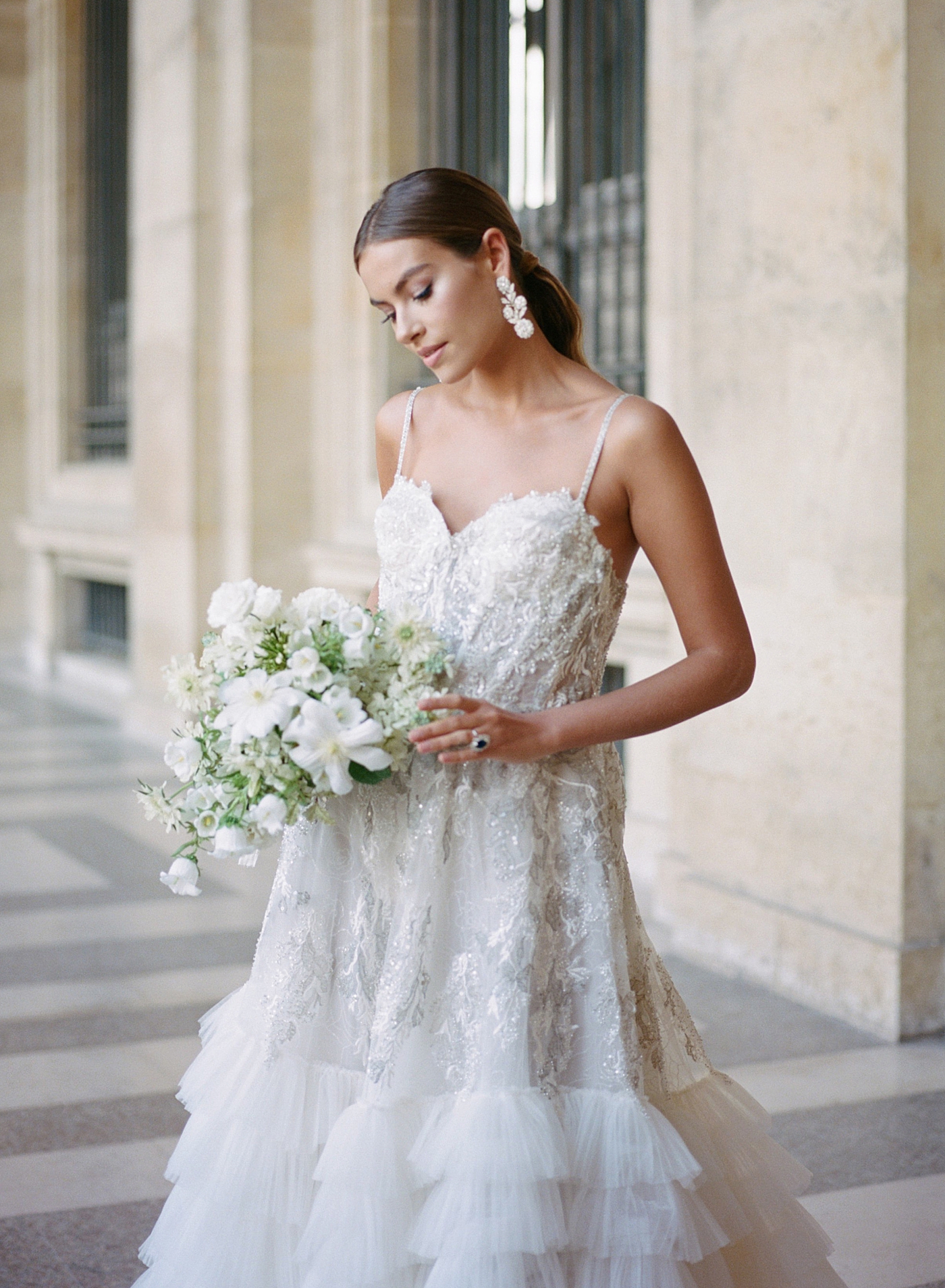 Close up bride standing in the outside hallway of the Louvre with a bouquet and engagement ring | Image by Hope Helmuth Photography