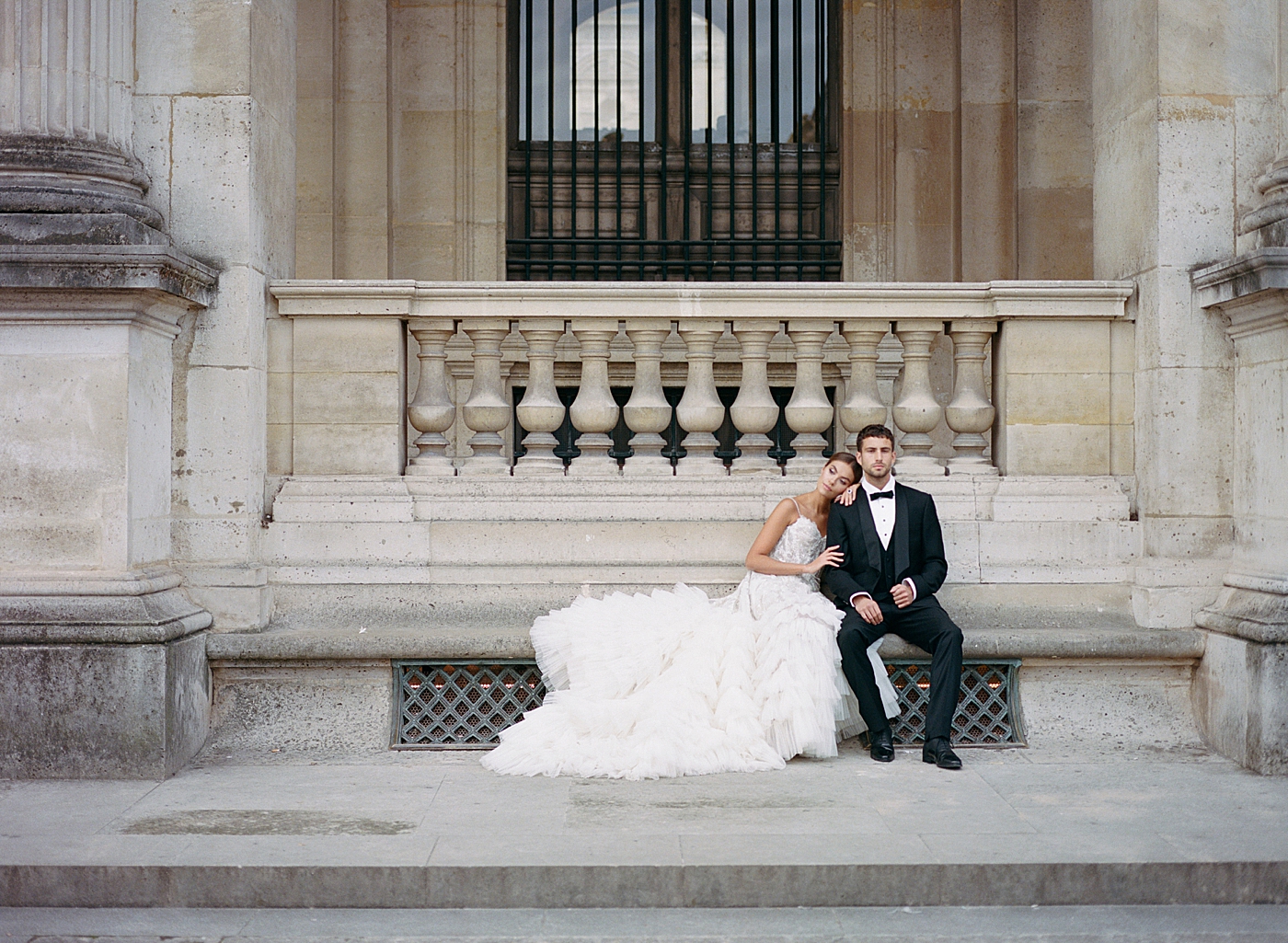 Bride and groom sitting together on a concrete bench | Image by Hope Helmuth Photography