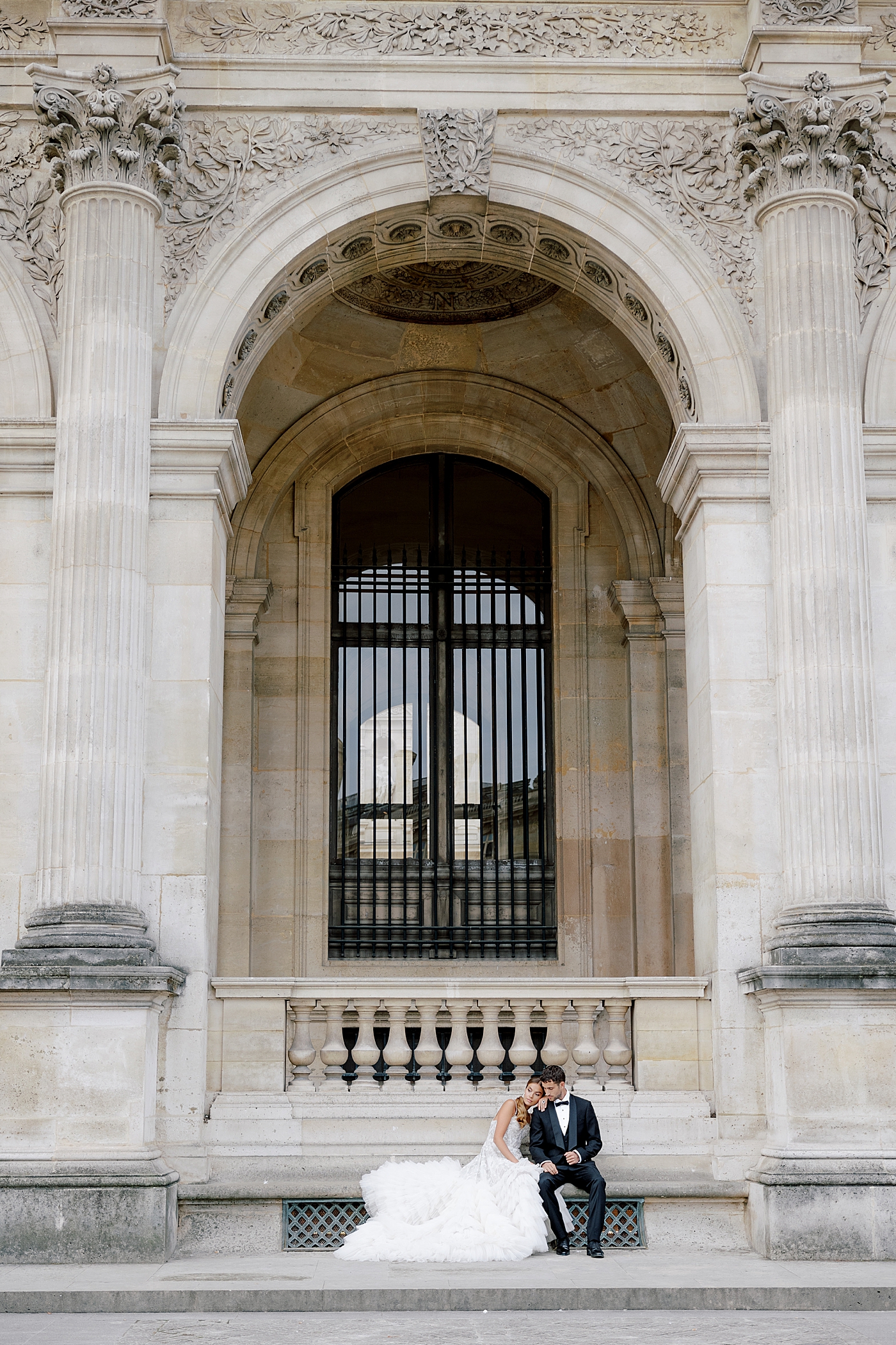 Bride and groom sitting together on a concrete bench during a Paris Elopement | Image by Hope Helmuth Photography