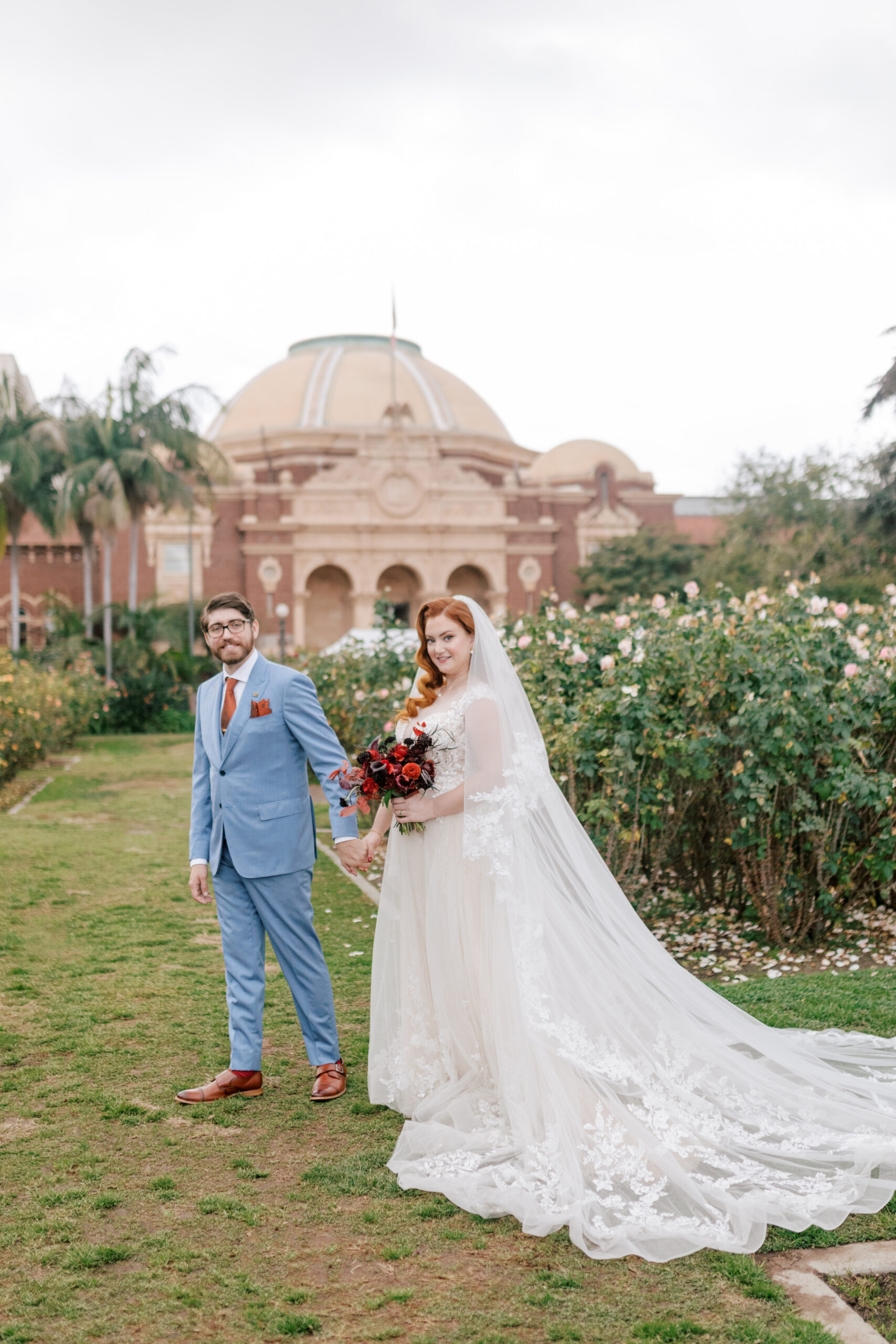 Bride and groom walking through a rose garden | Image by Hope Helmuth Photography