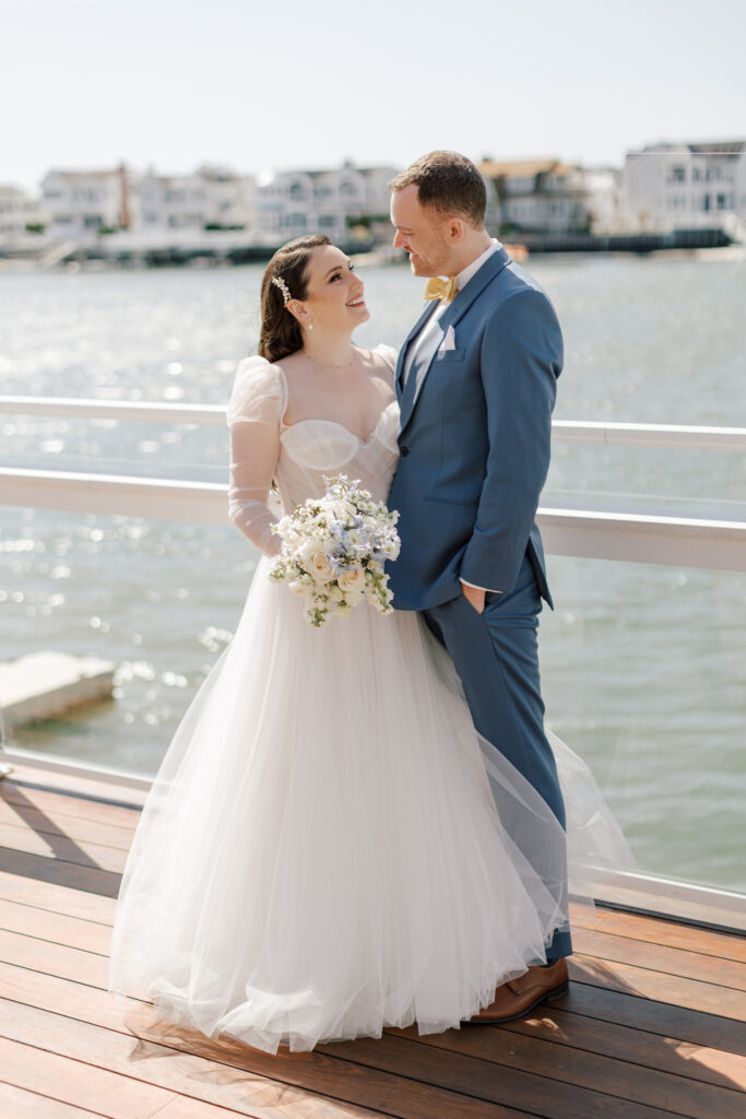 Bride and groom embracing by the water at a Stone Harbor wedding venue, The Reeds at Shelter Haven