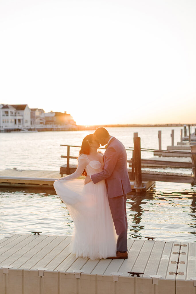 Bride and groom embracing by the water at a Stone Harbor wedding venue, The Reeds at Shelter Haven