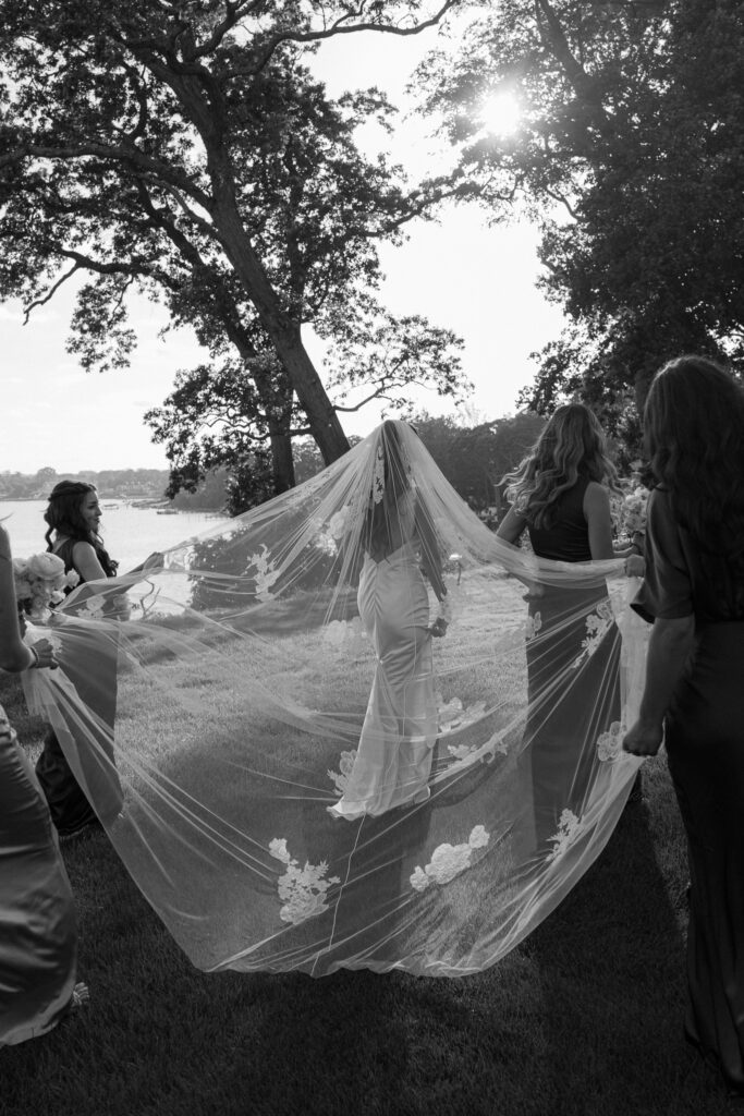 coastal-waterfront-tented-wedding-photos-38 Bride in a Danielle Frankel gown with lace veil walking along the waterfront at a private estate tented wedding.