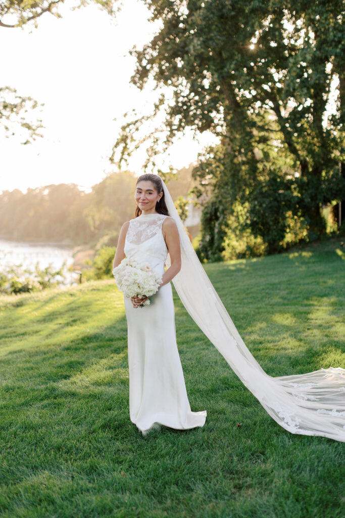 coastal-waterfront-tented-wedding-photos-43 Bride in a Danielle Frankel gown with lace veil walking along the waterfront at a private estate tented wedding.